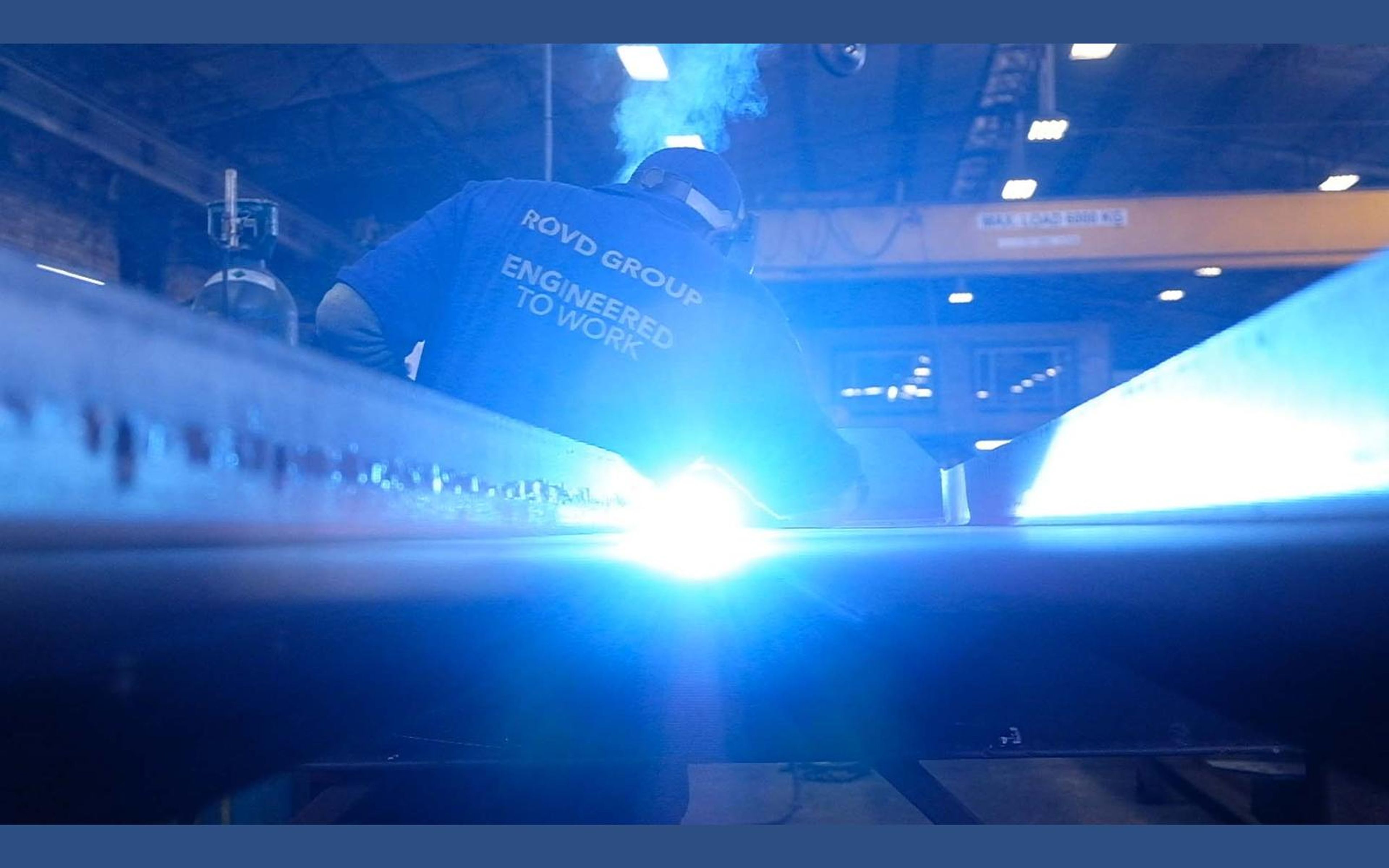 Welder leaning over steel with a blue arc and sparks