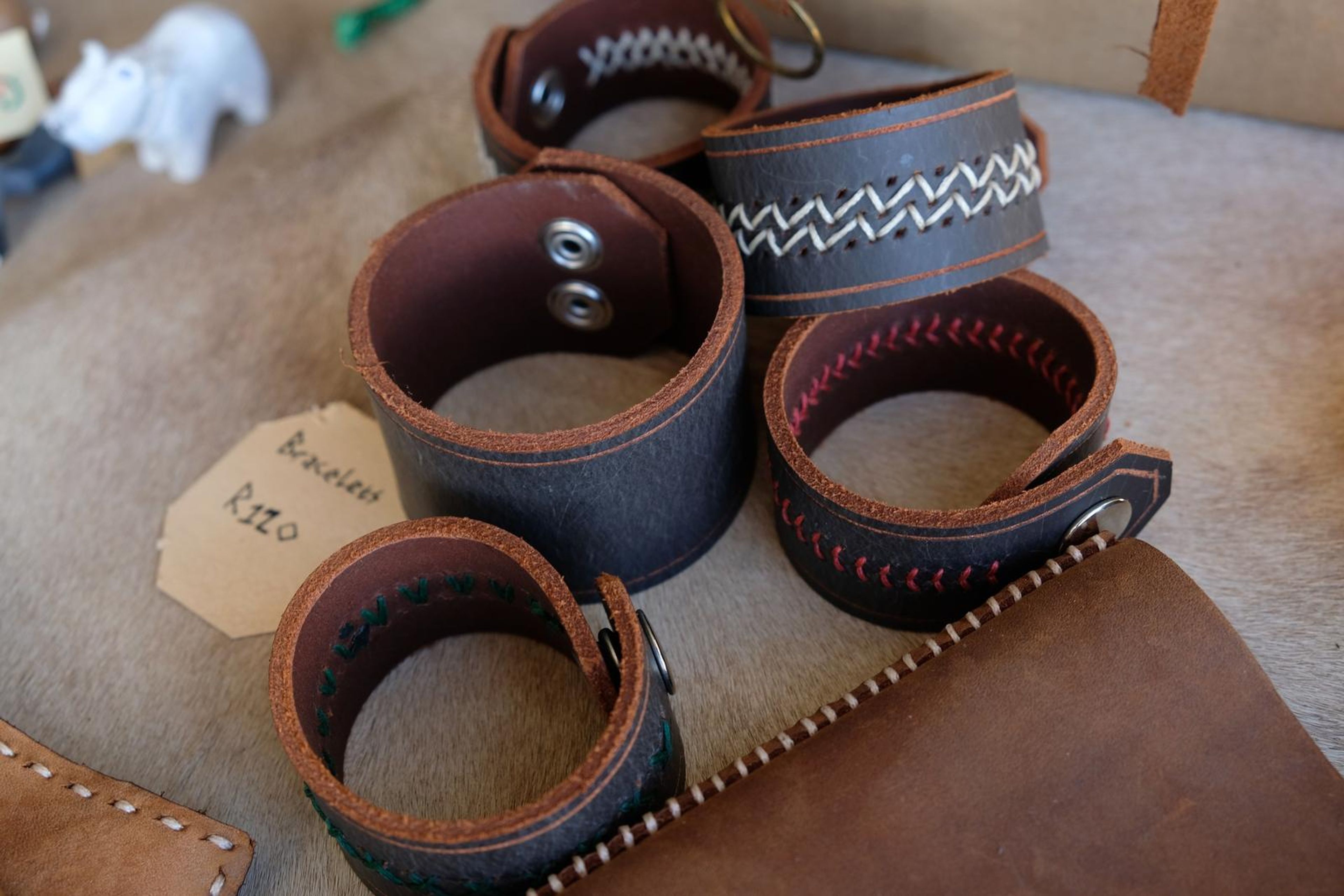 Black leather cuffs with white and red hand-stitched patterns and snap studs