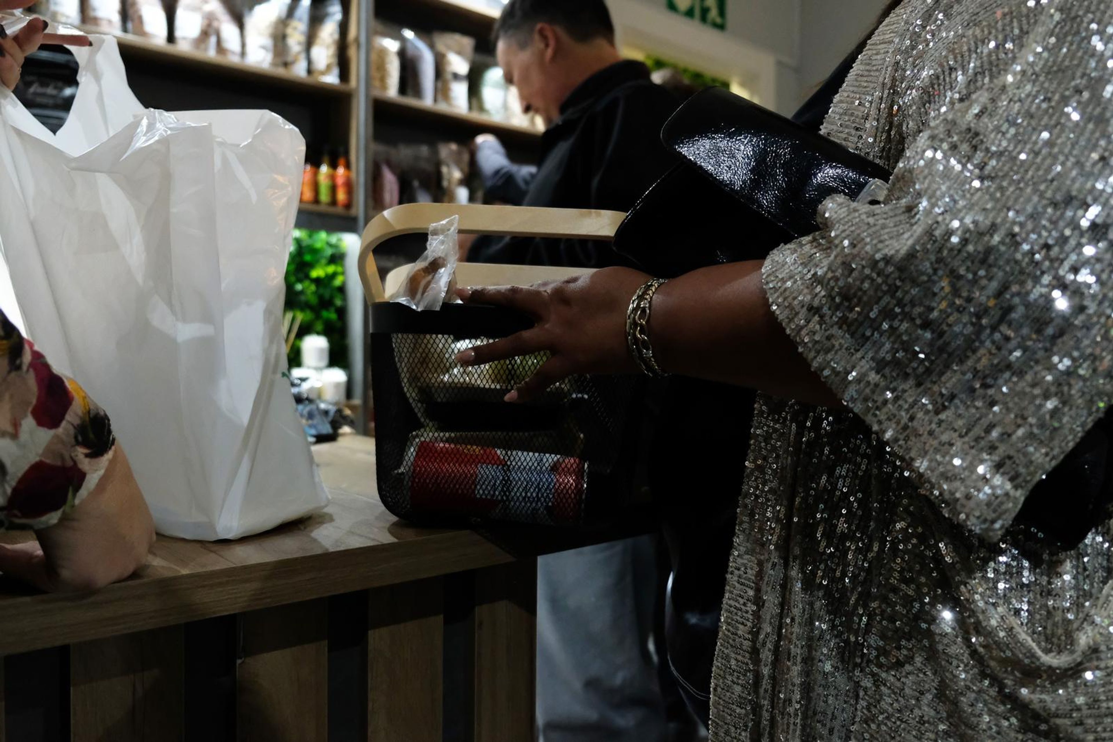 Hands placing items in a basket at the counter beside a sequin sleeve
