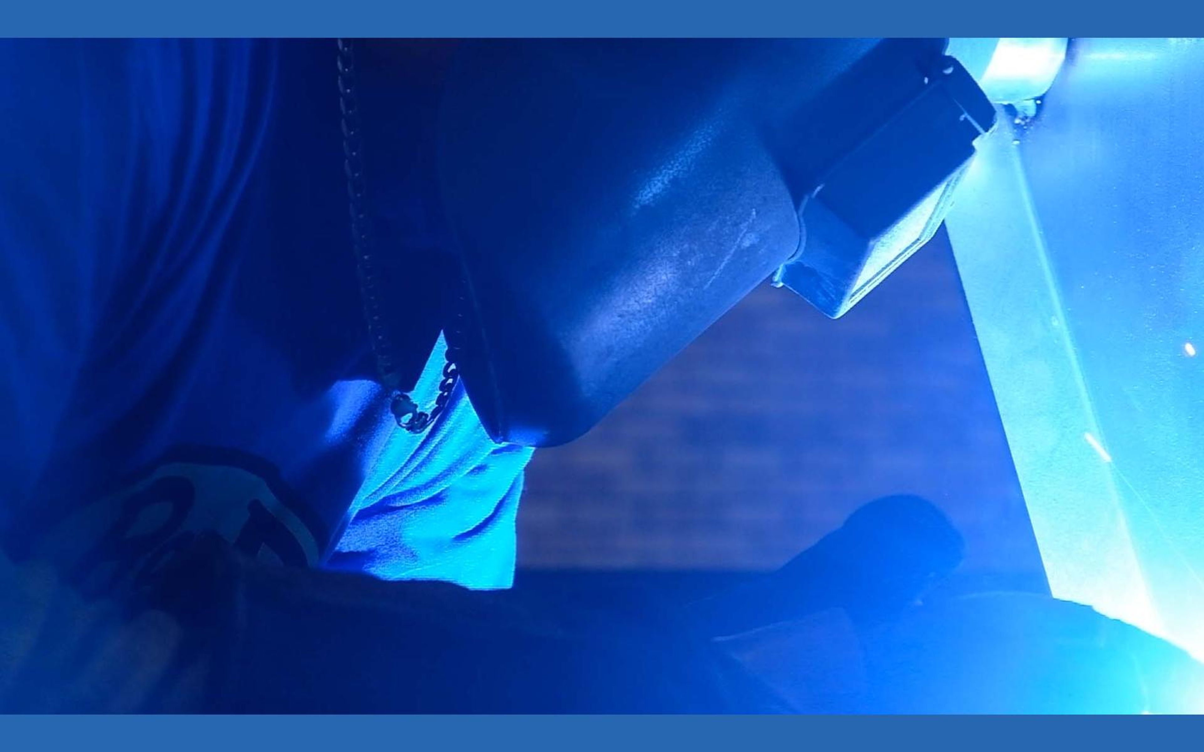 Welder leaning over steel with a blue arc and sparks