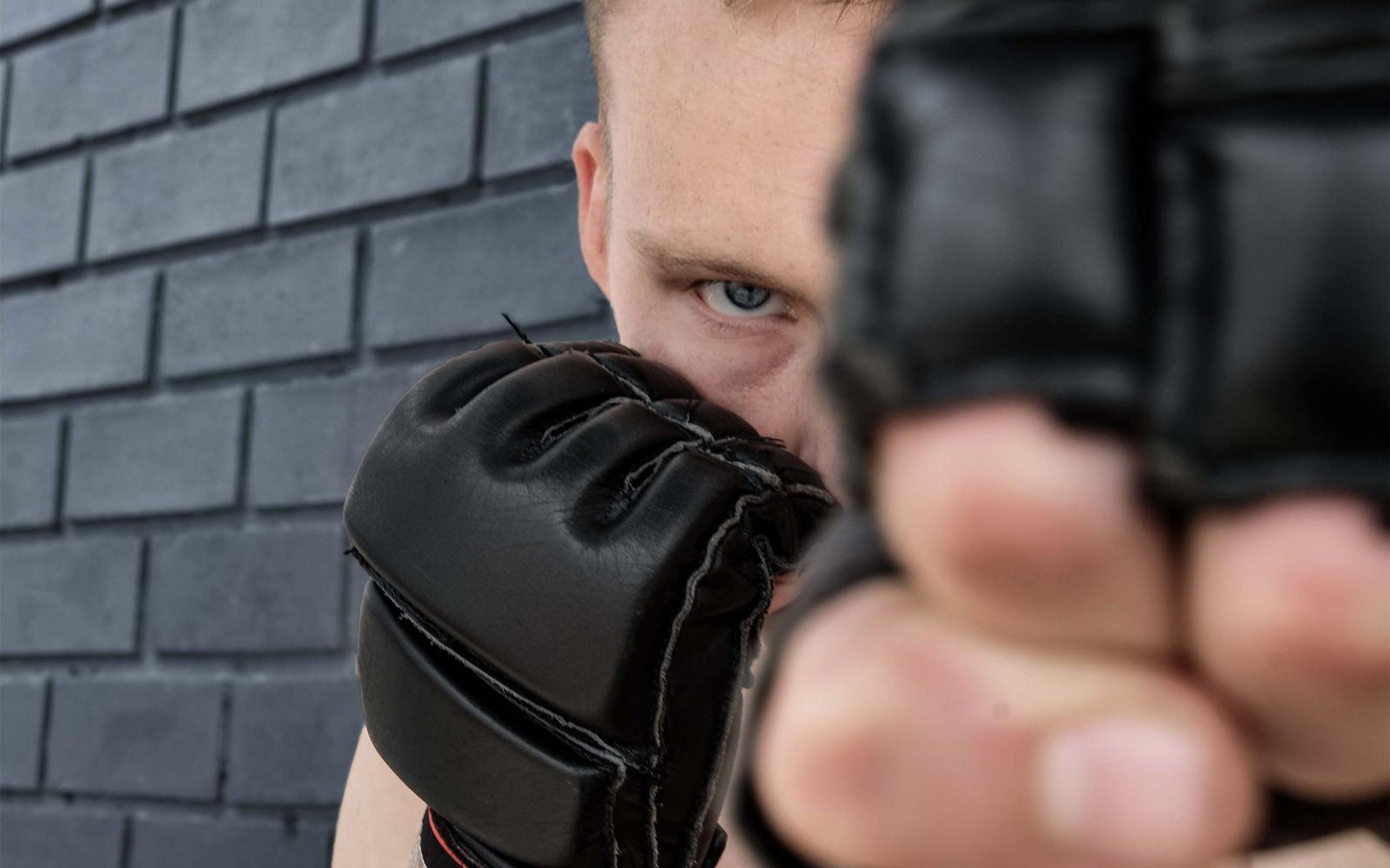 Gloved fist in front of the fighter's eyes against dark grey brick