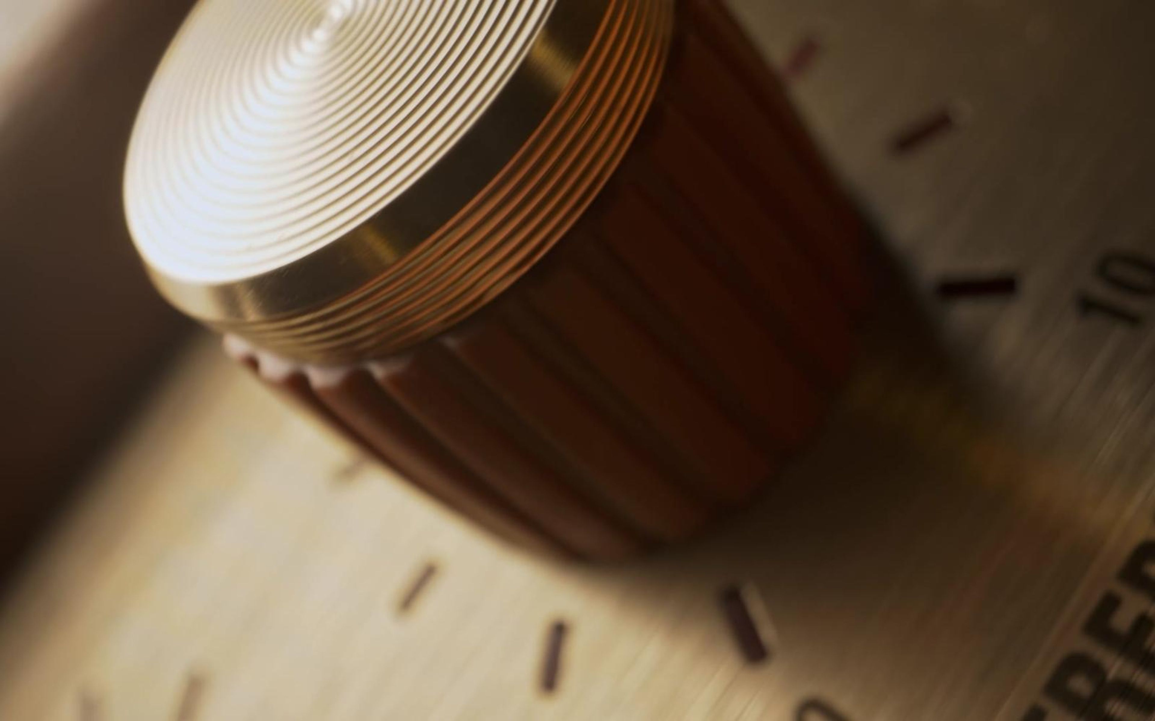 Gold and wood amp knob in warm light with the treble dial markings behind it