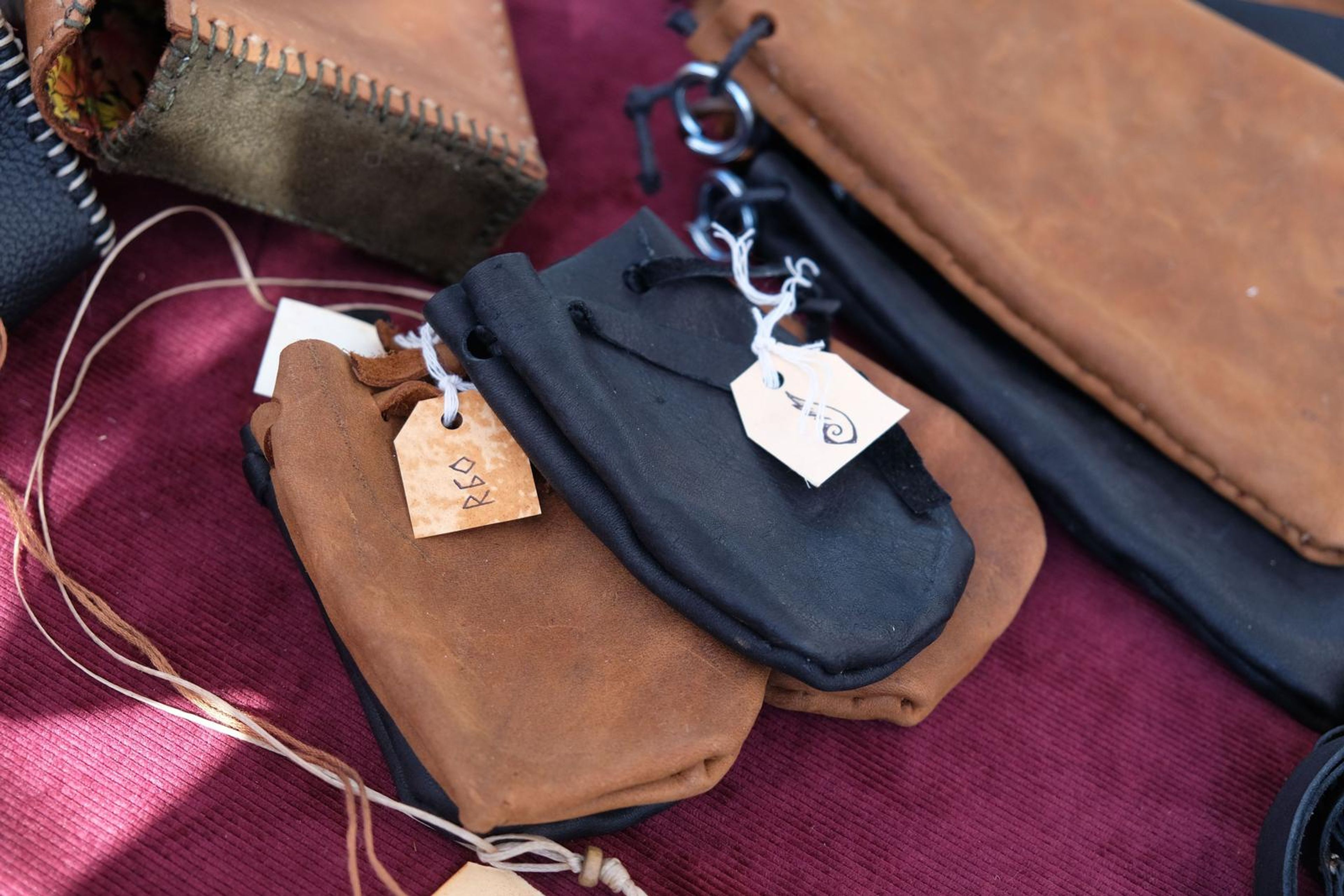 Drawstring leather pouches in tan and black with handwritten tags