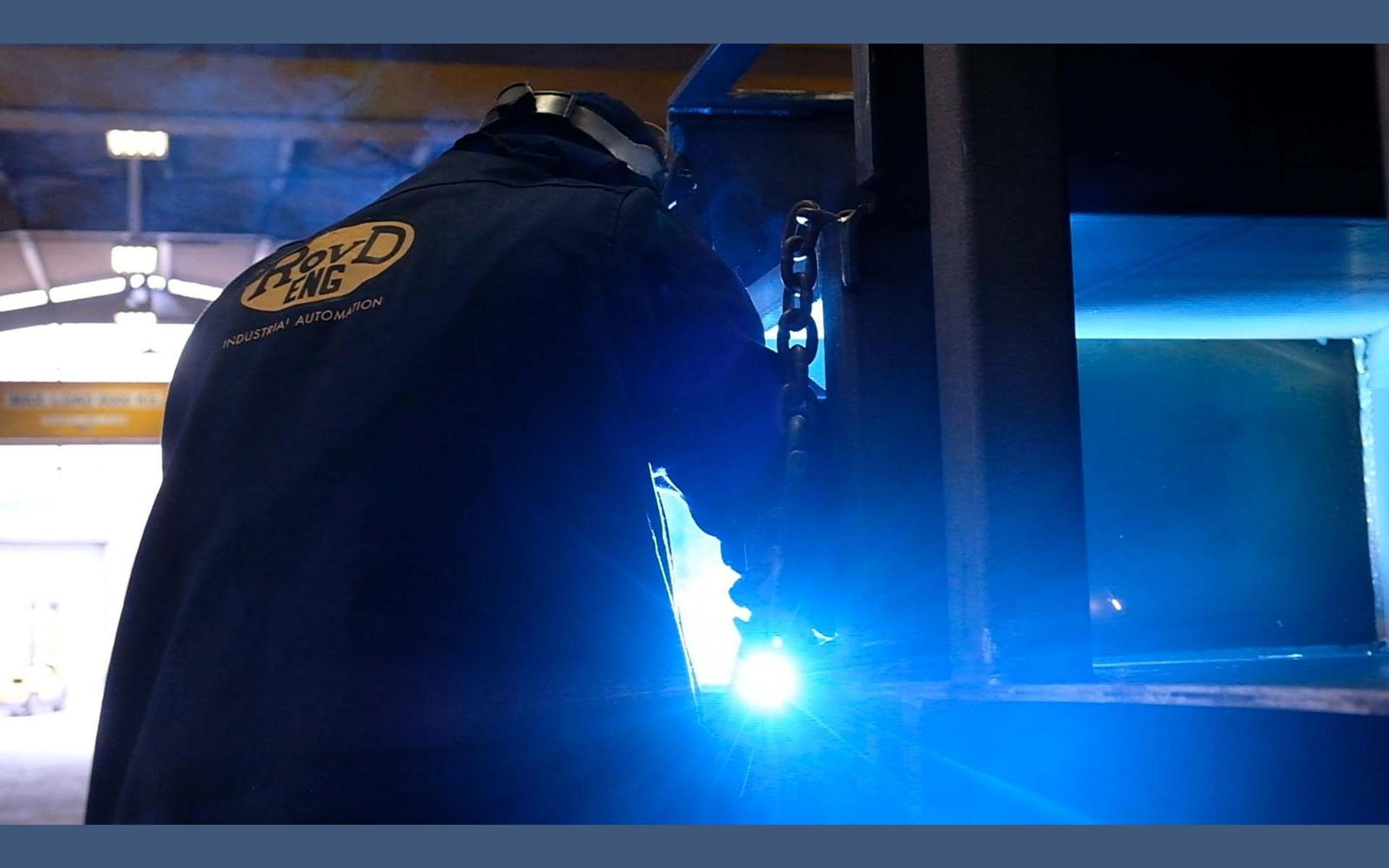 Welding glow lighting the steel and the welder's mask