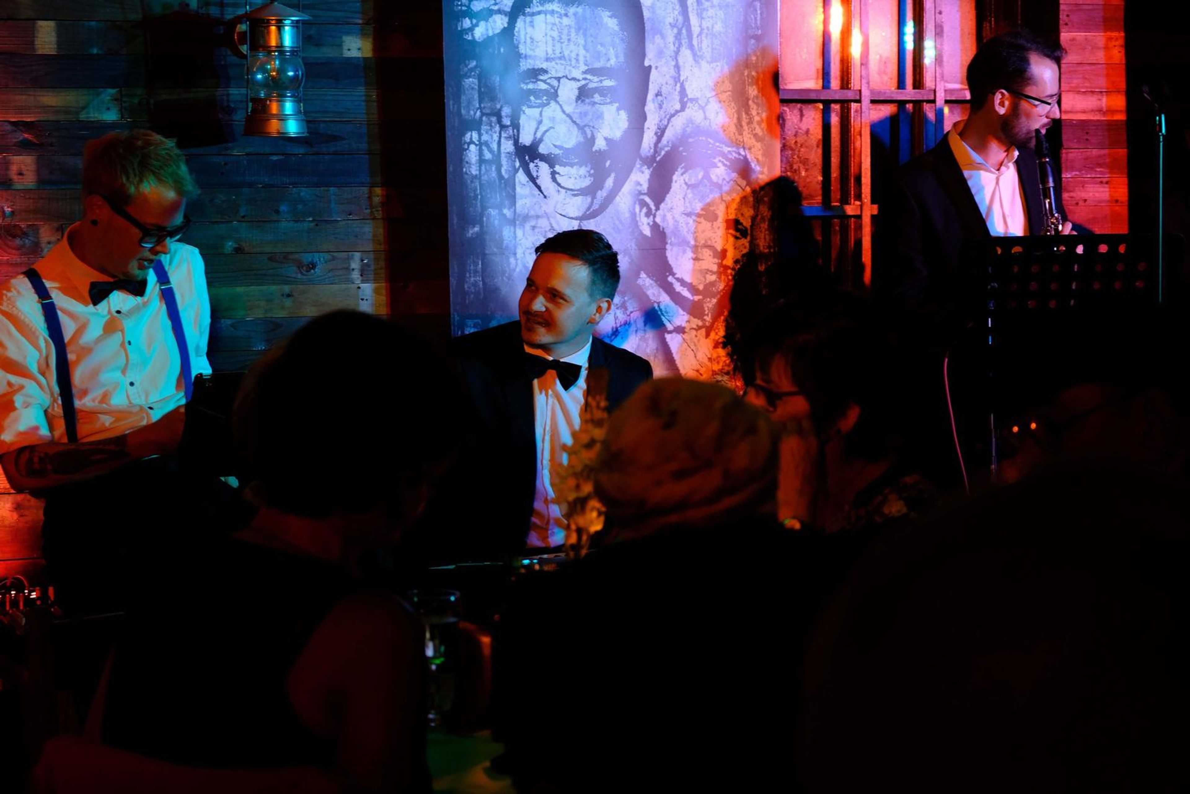 Band on stage under a mural of jazz legends