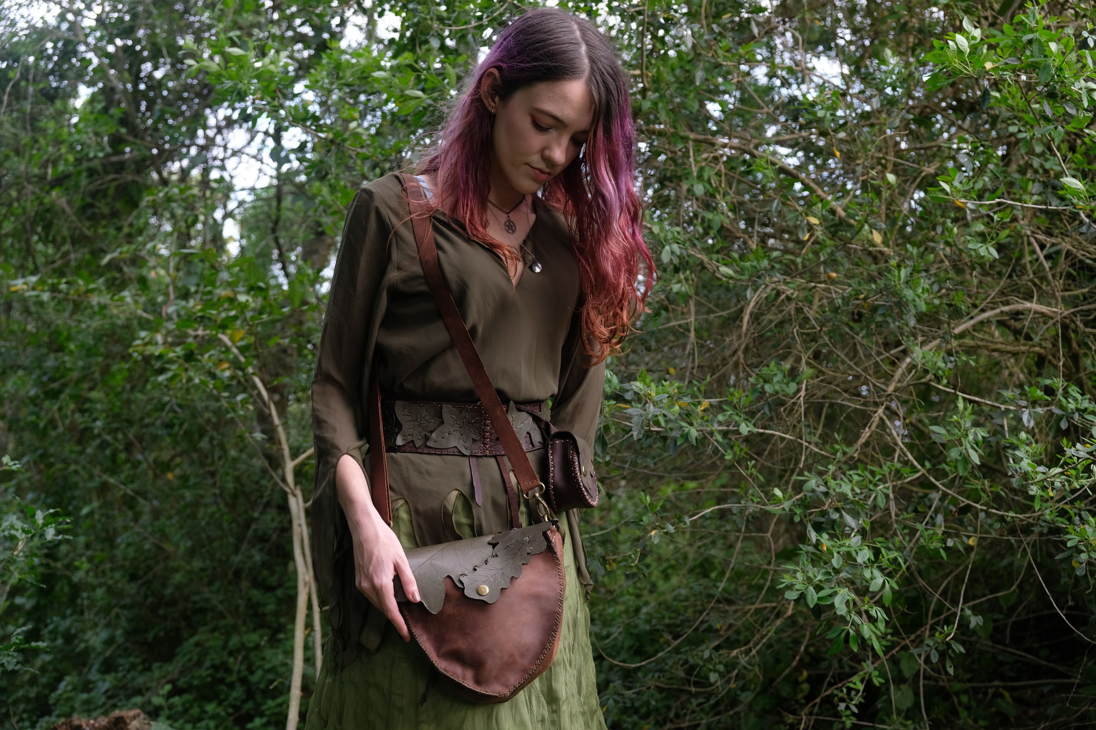 Woman with a leather bag looking down among trees