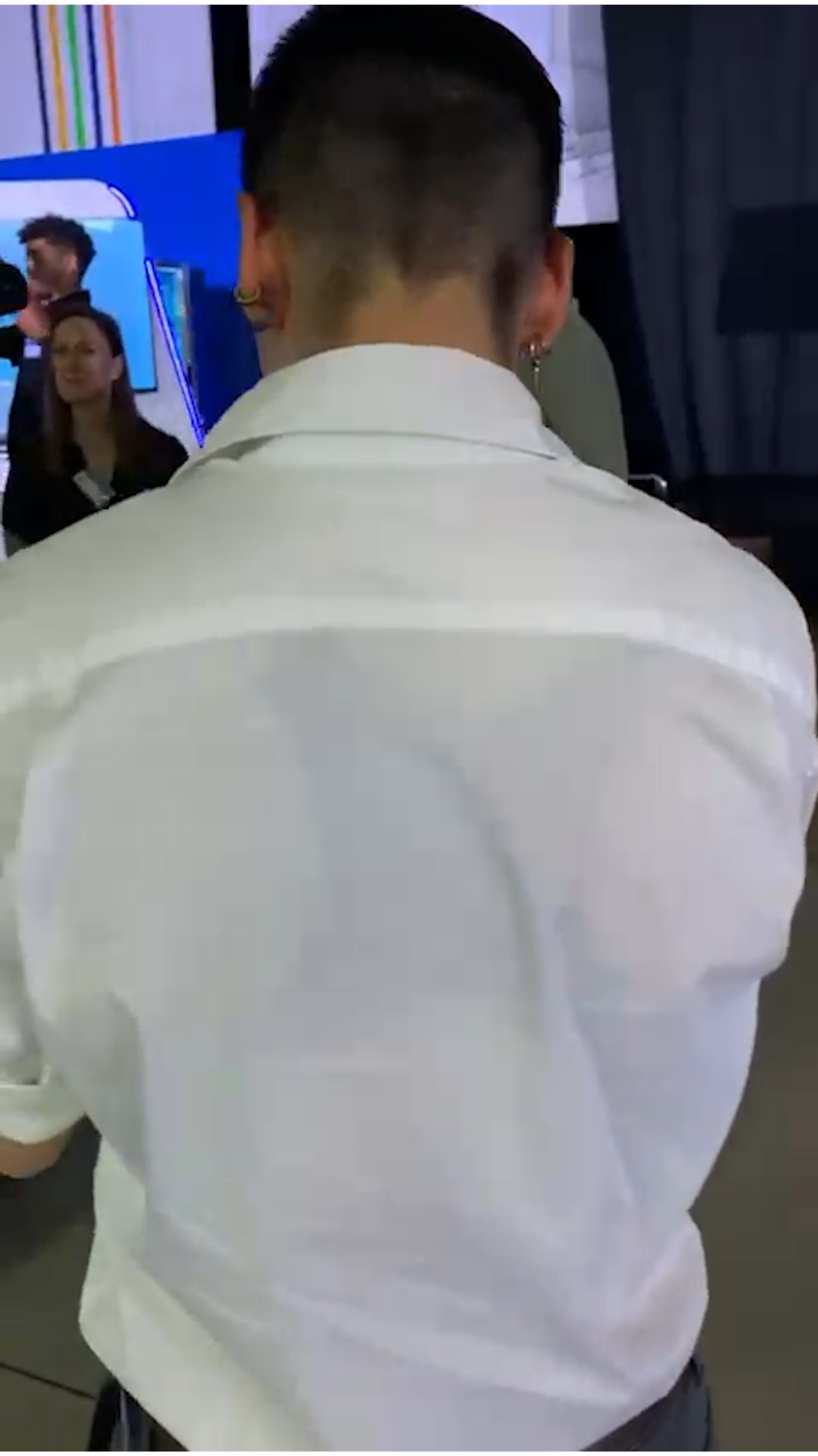 Behind the scenes at the expo, a man in a white shirt seen from behind among visitors
