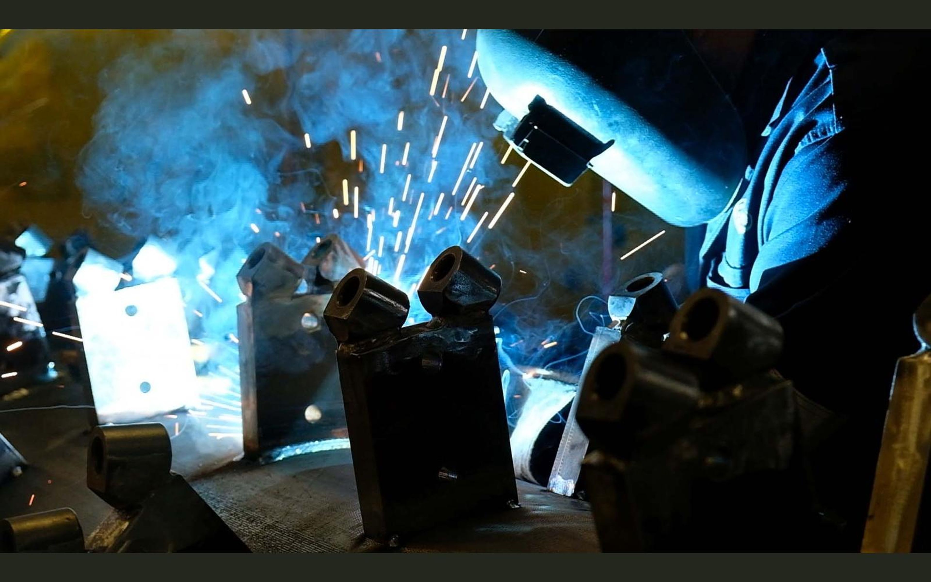 Brackets arranged around a drum while a welder works