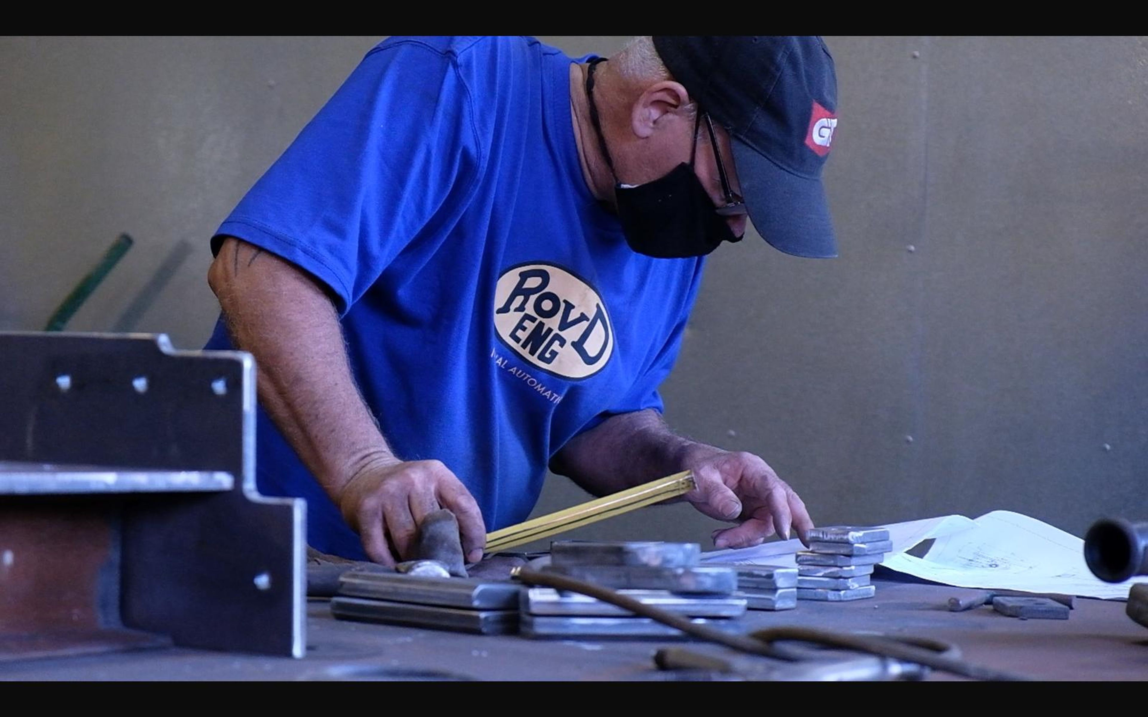 Fabricator measuring a steel bracket