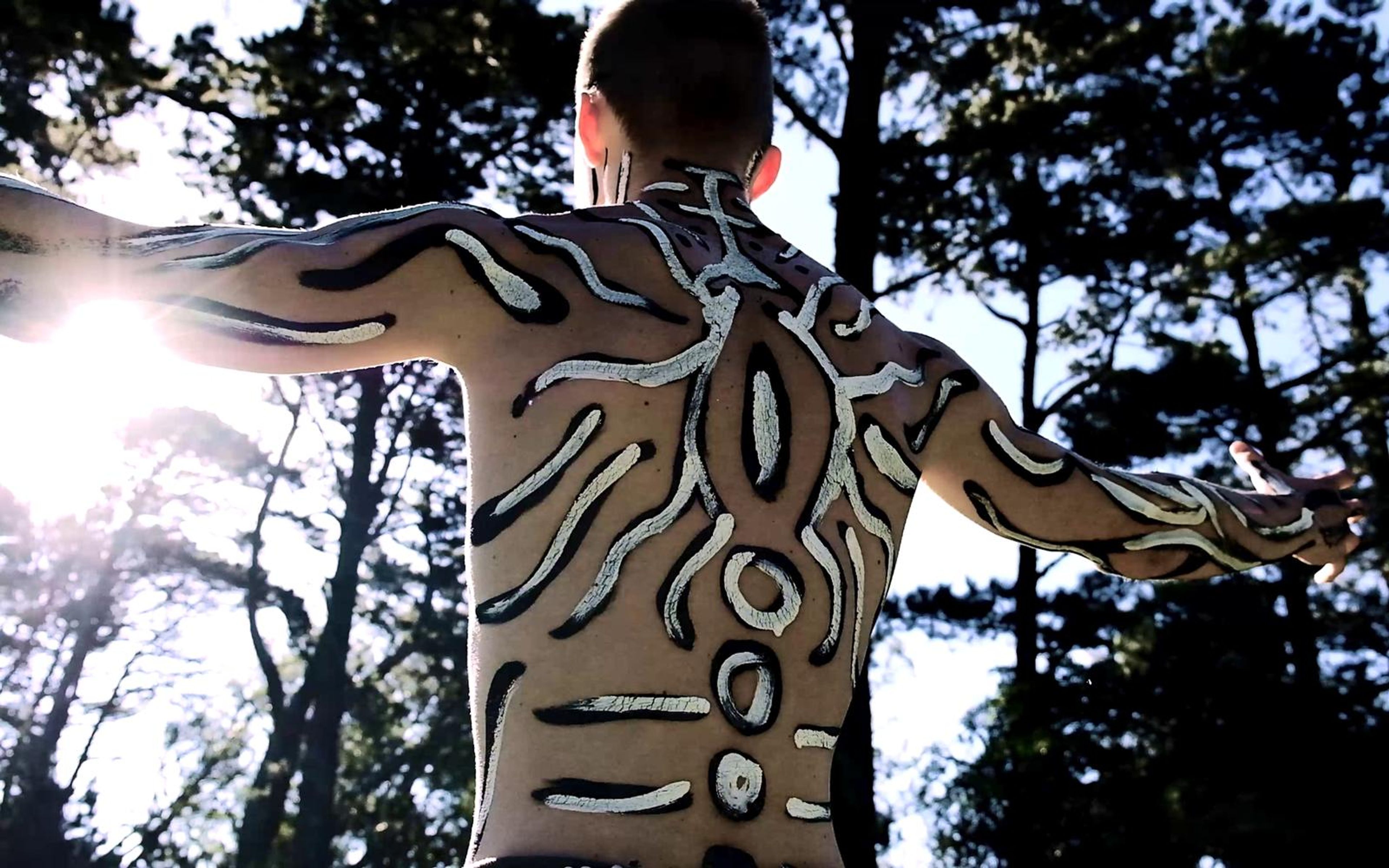 Painted back with leopard-like markings and arms open and sun flare at the left
