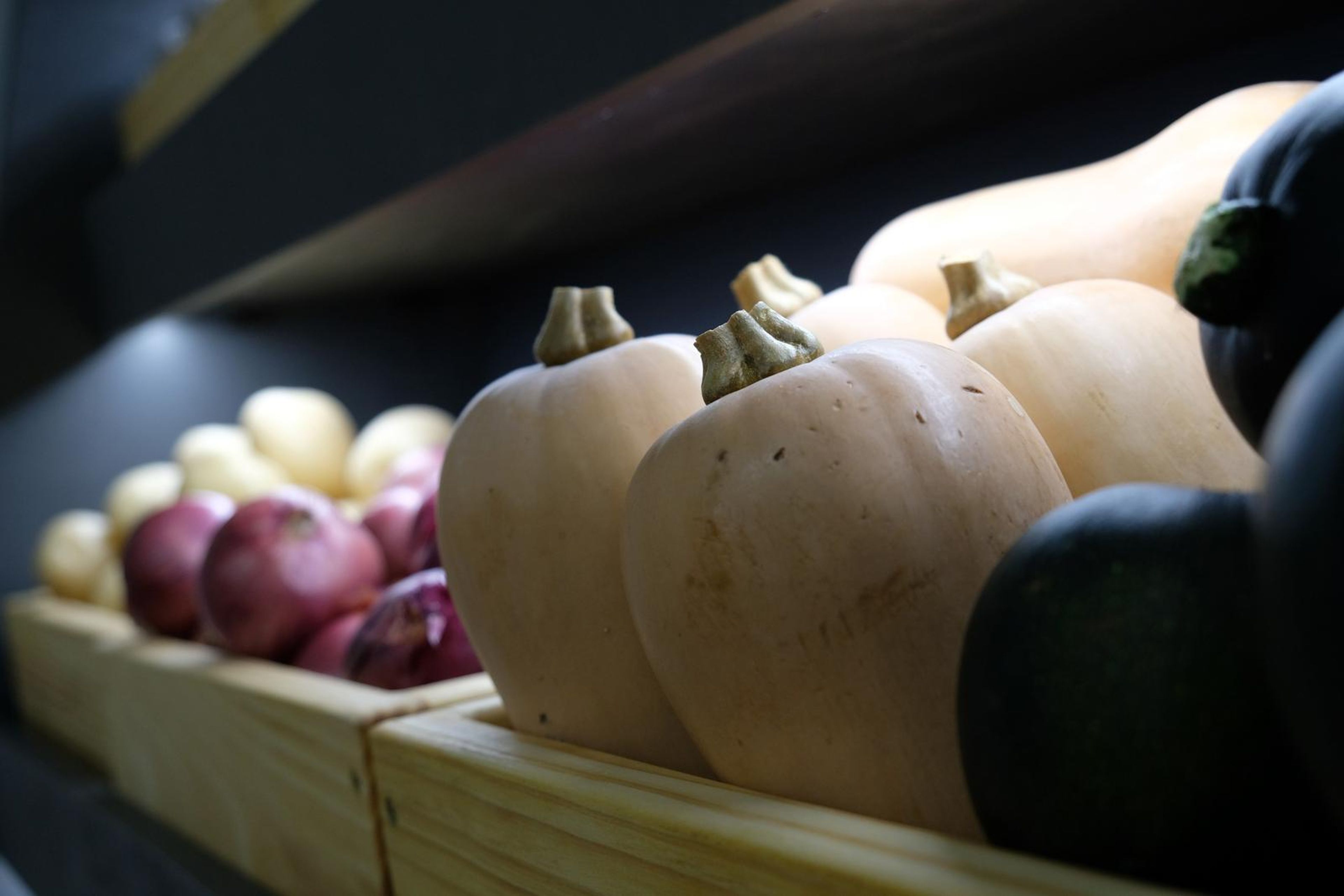 Butternut squash, red onions and courgettes in wooden produce crates
