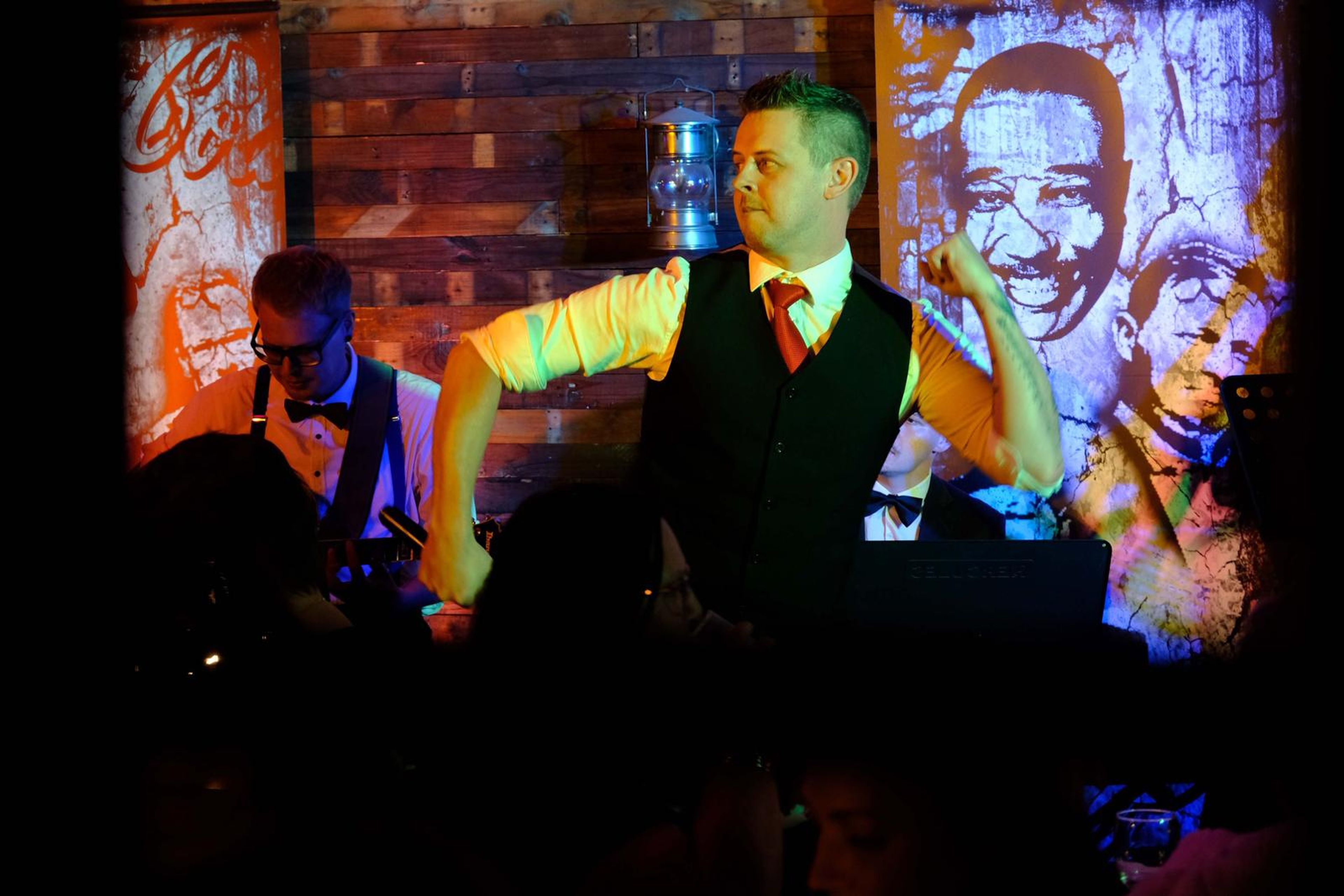 Singer with his arm on his hip in front of a smiling mural