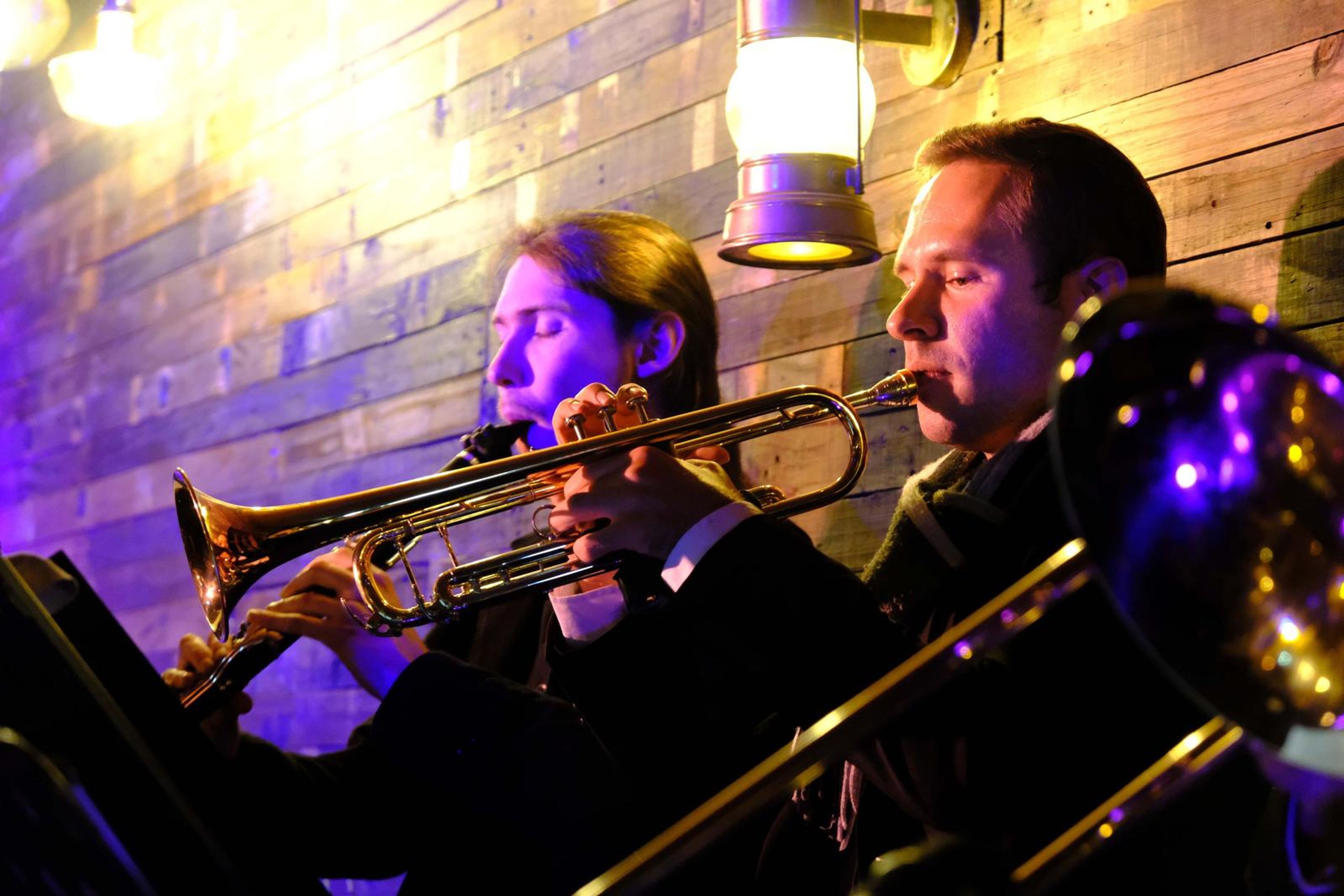 Trumpeter and trombonist playing together by a lantern