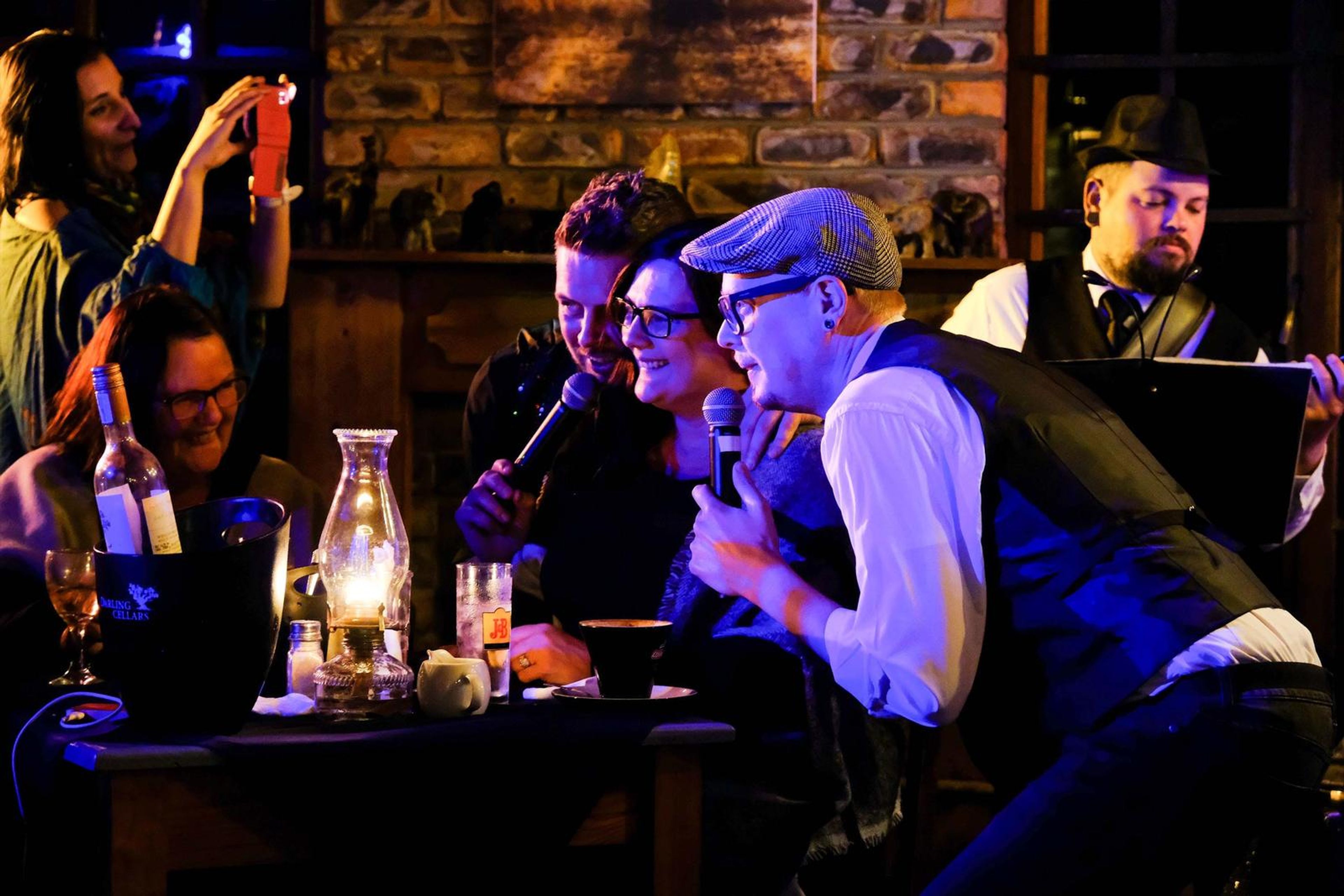 Singers leaning in to a table of guests with the microphone
