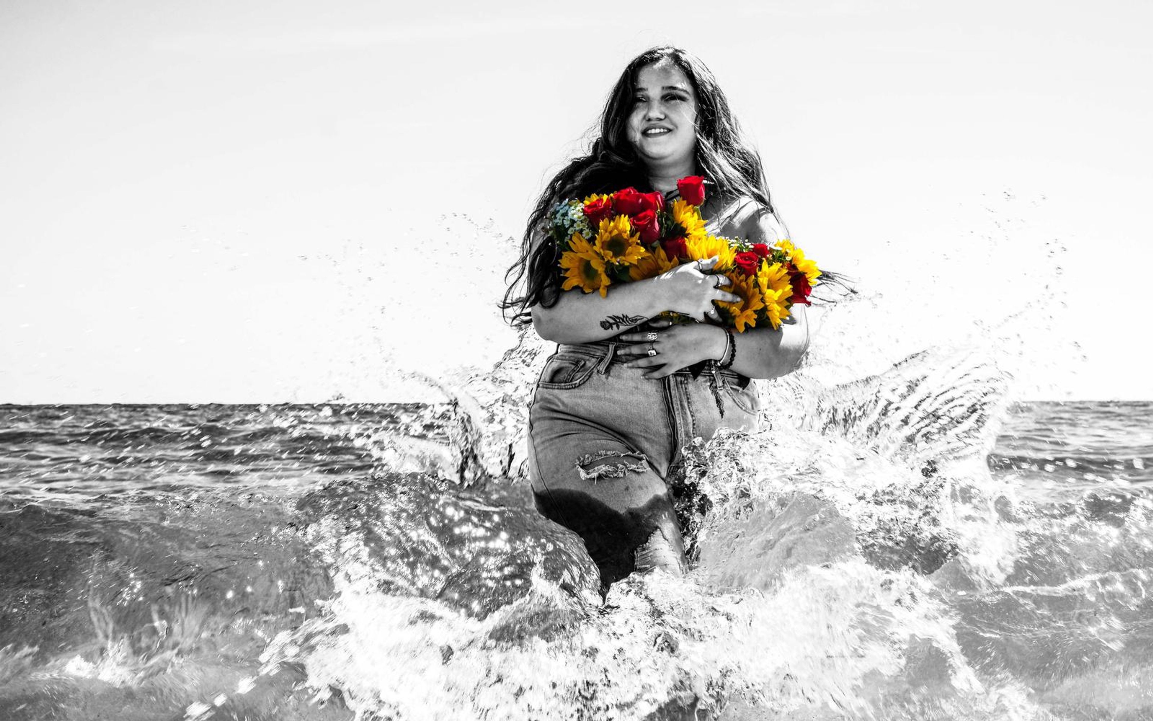 Black and white splash frame, model laughing with bouquet, spray frozen around her legs