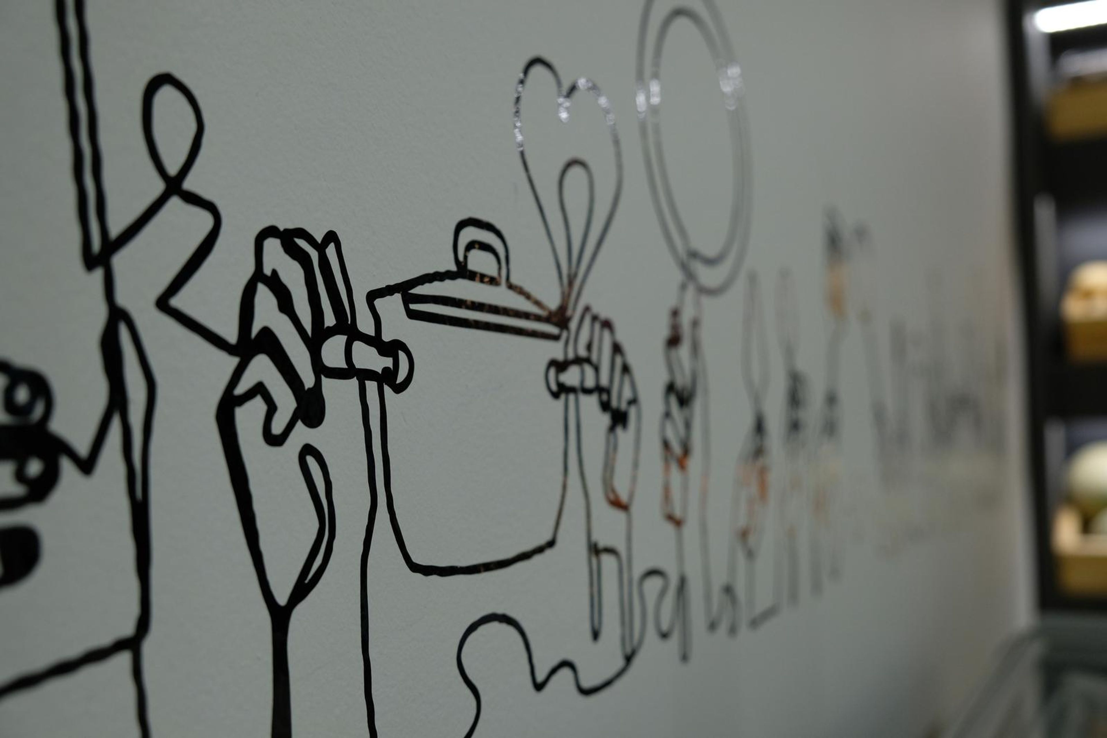 Hand-drawn line art mural of cooking on the store wall