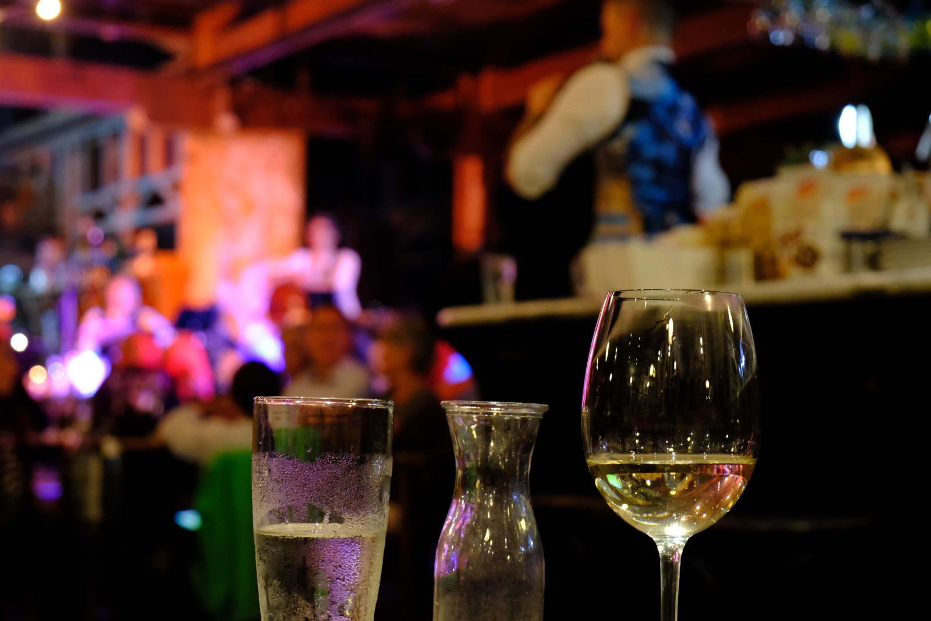 Glass of white wine in front of a cheese table, with the singer in the background