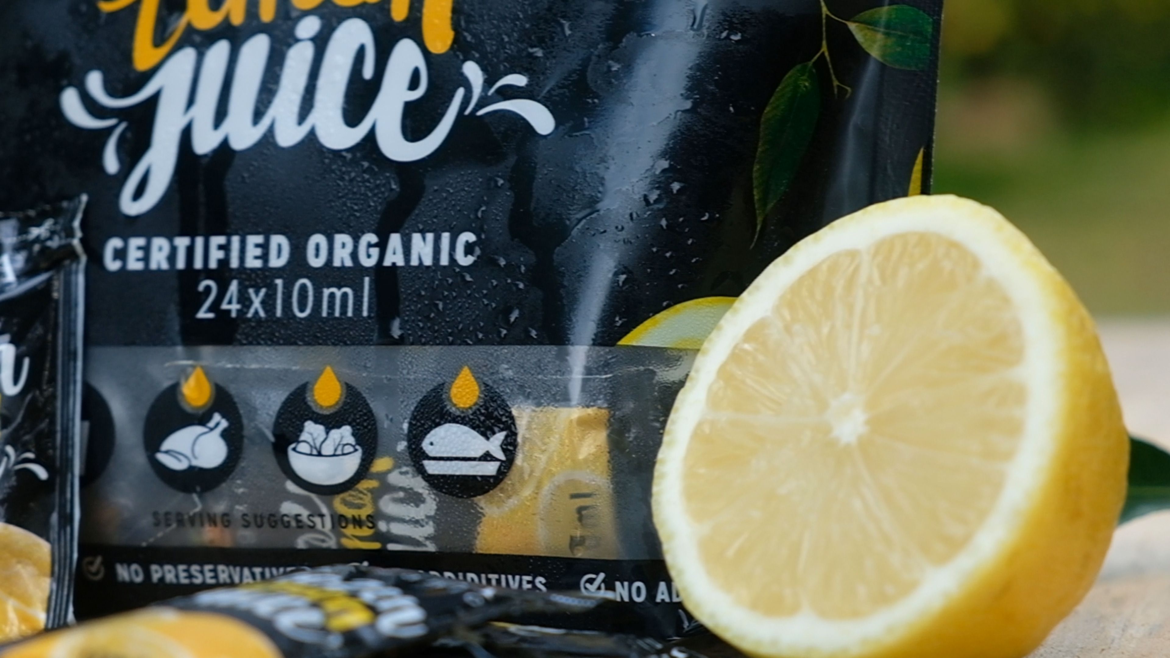 Close-up of a lemon juice sachet pack with serving suggestion icons and a halved lemon