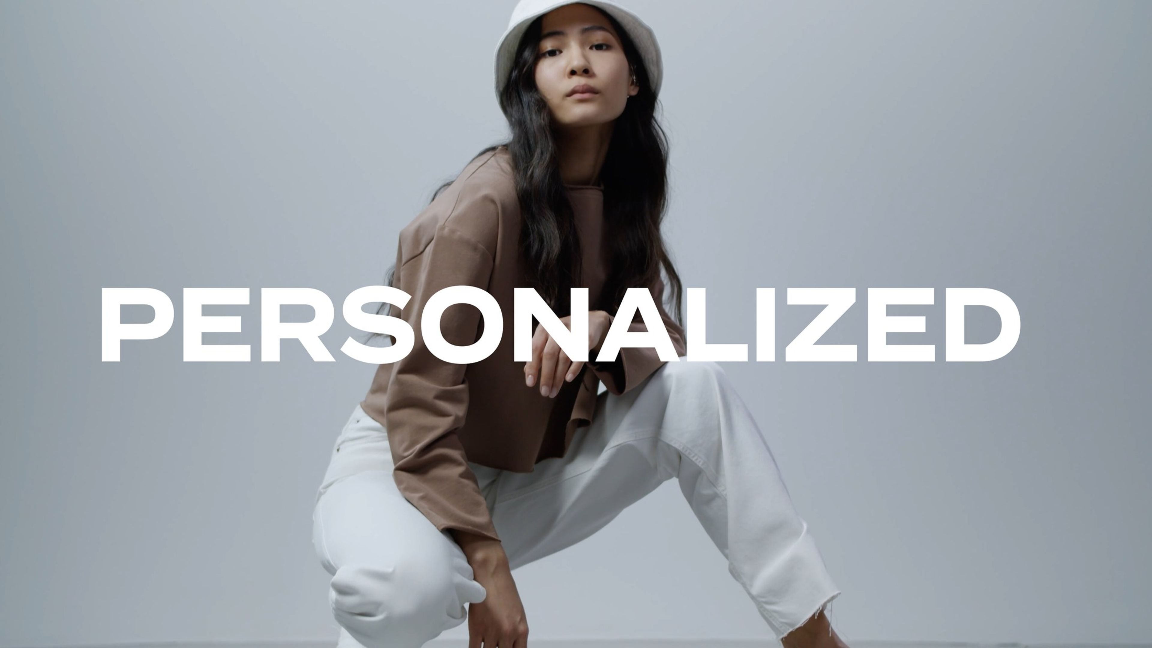 Woman in a brown jacket and white trousers crouching, with the text 'Personalized'