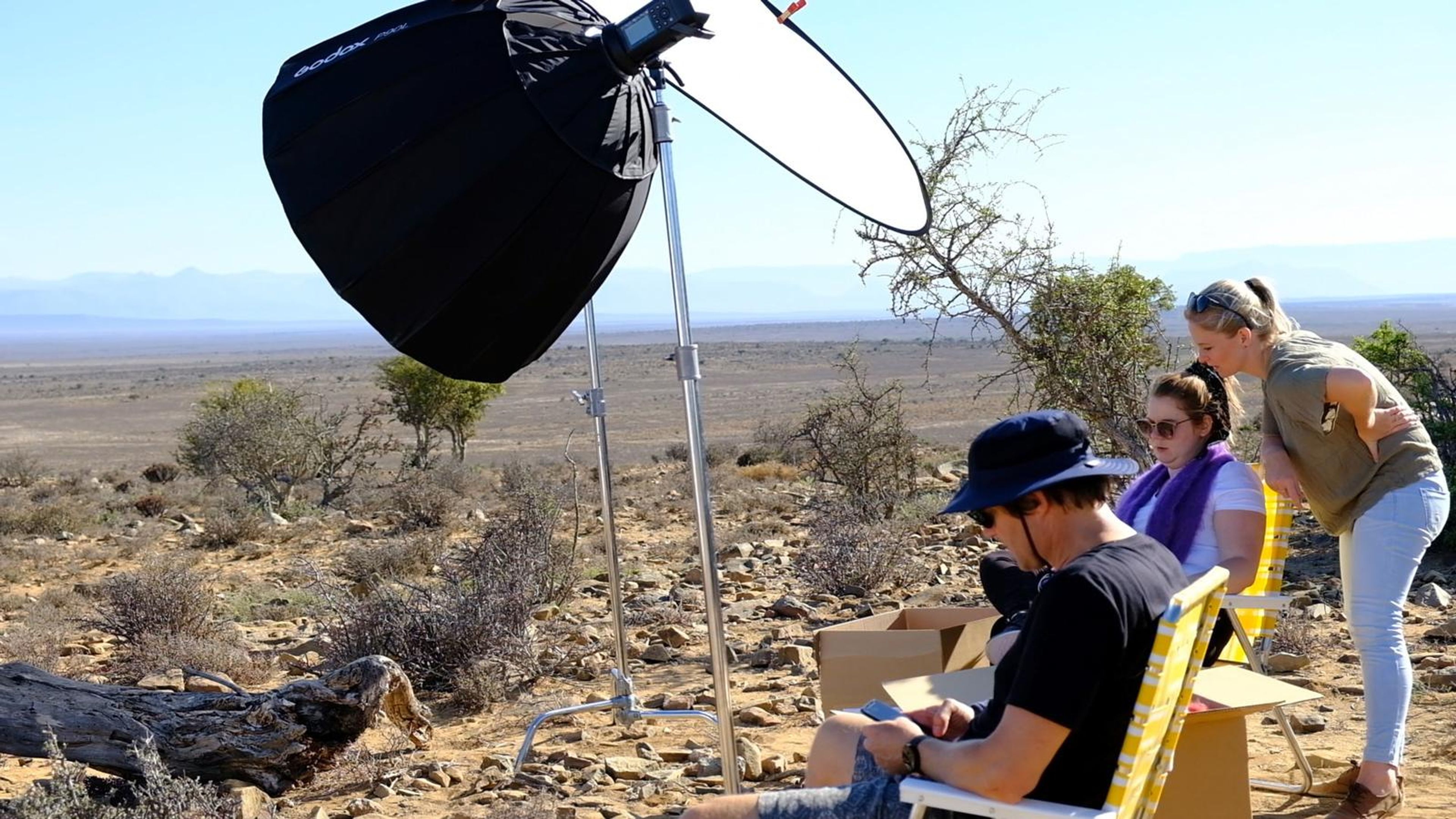 Crew resting beside a softbox and reflector during a break