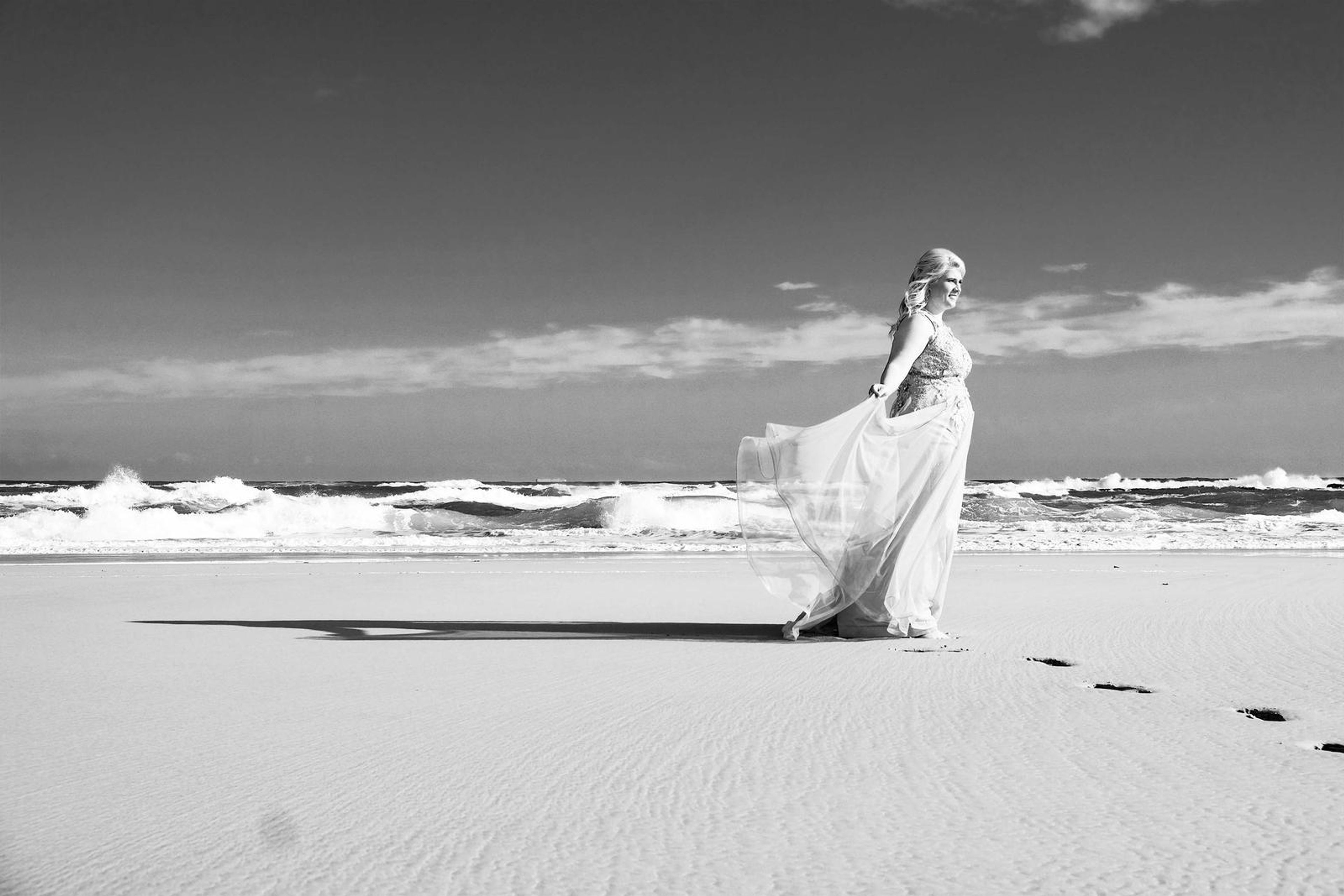 Black and white portrait with the gown twirling by the waves