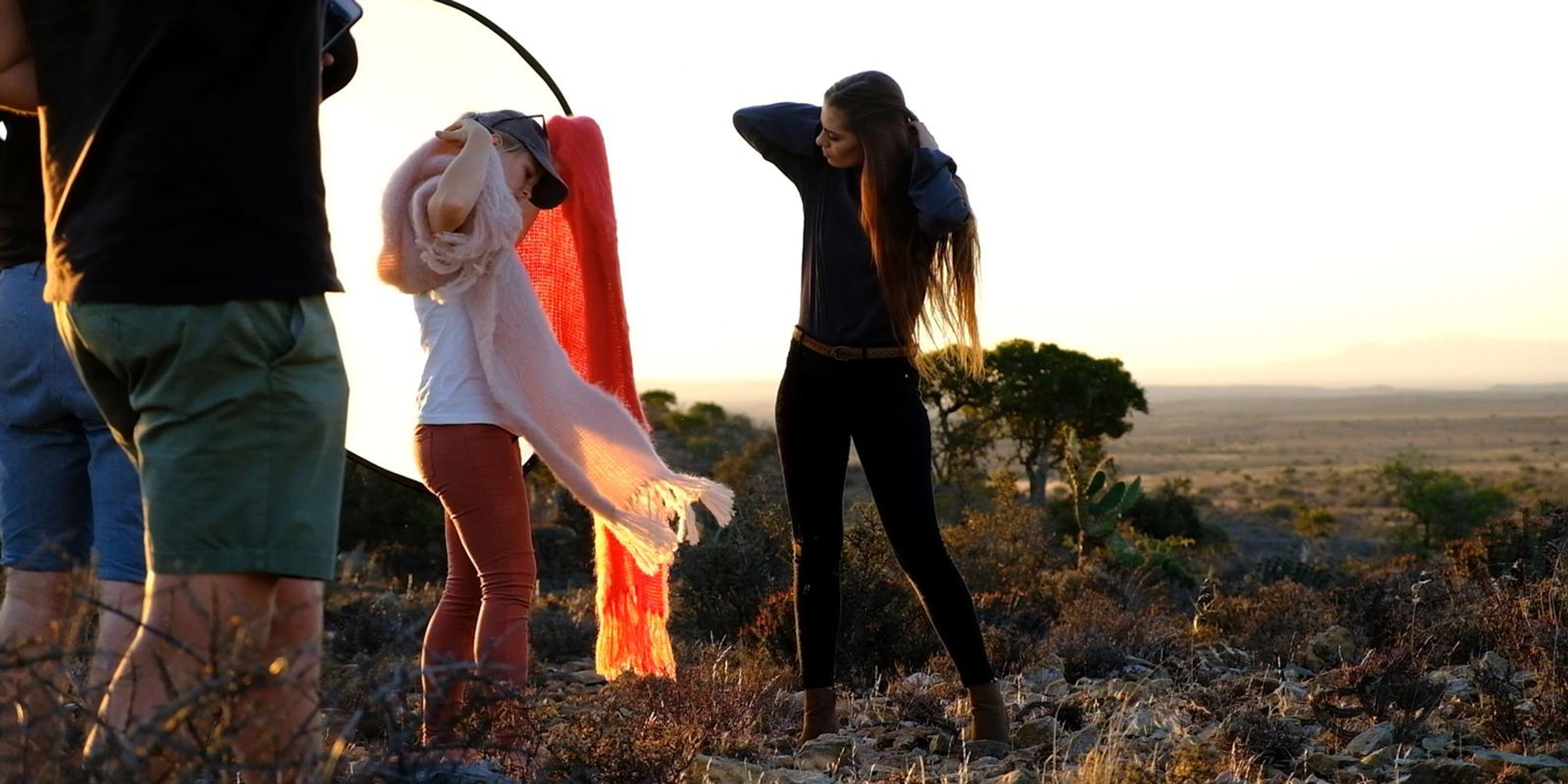 Stylists and crew arranging coral and pink wraps at golden hour