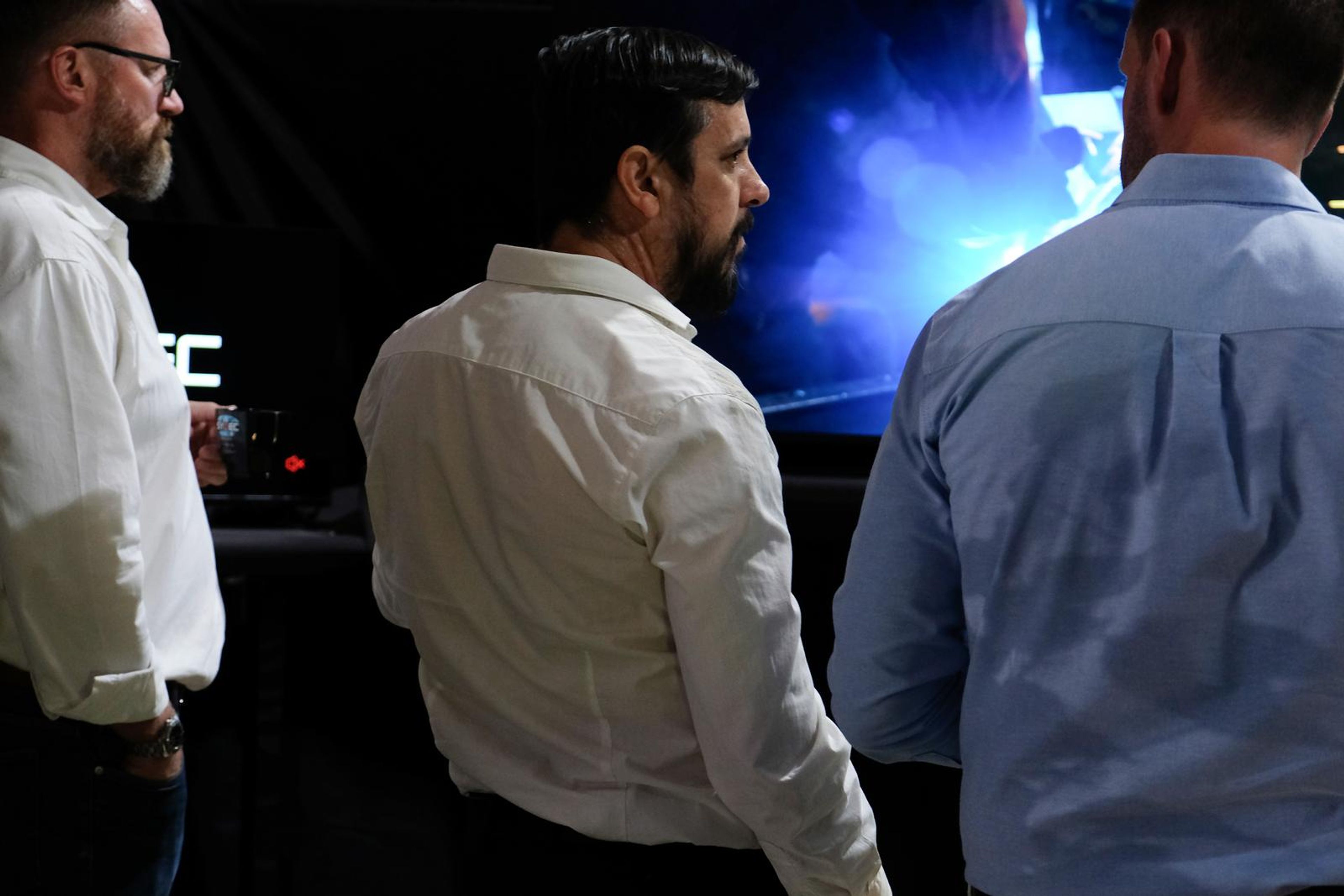 Two visitors and a presenter watching a digital simulation on a large screen