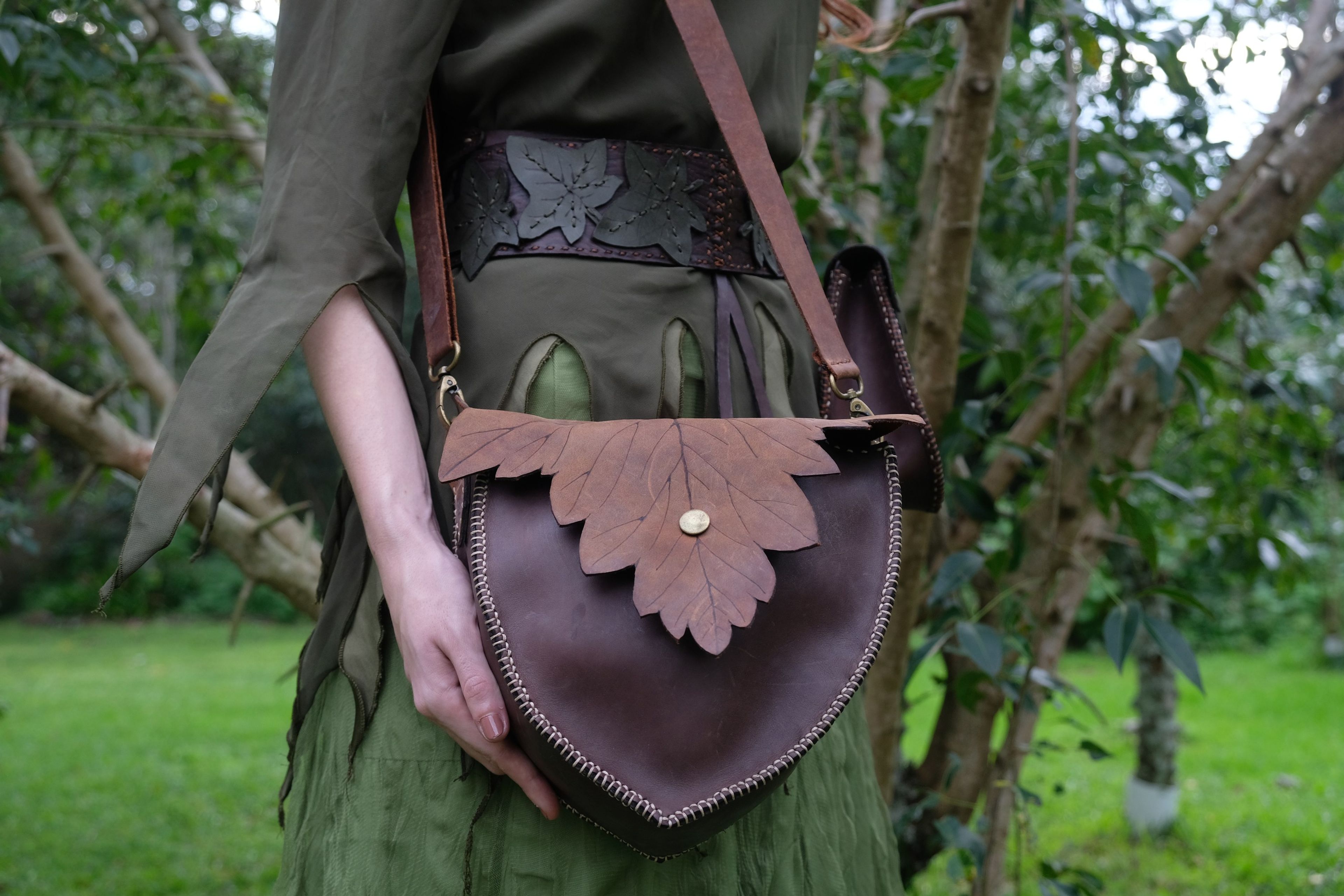 Woman in green holding a brown bag with a leaf-shaped flap