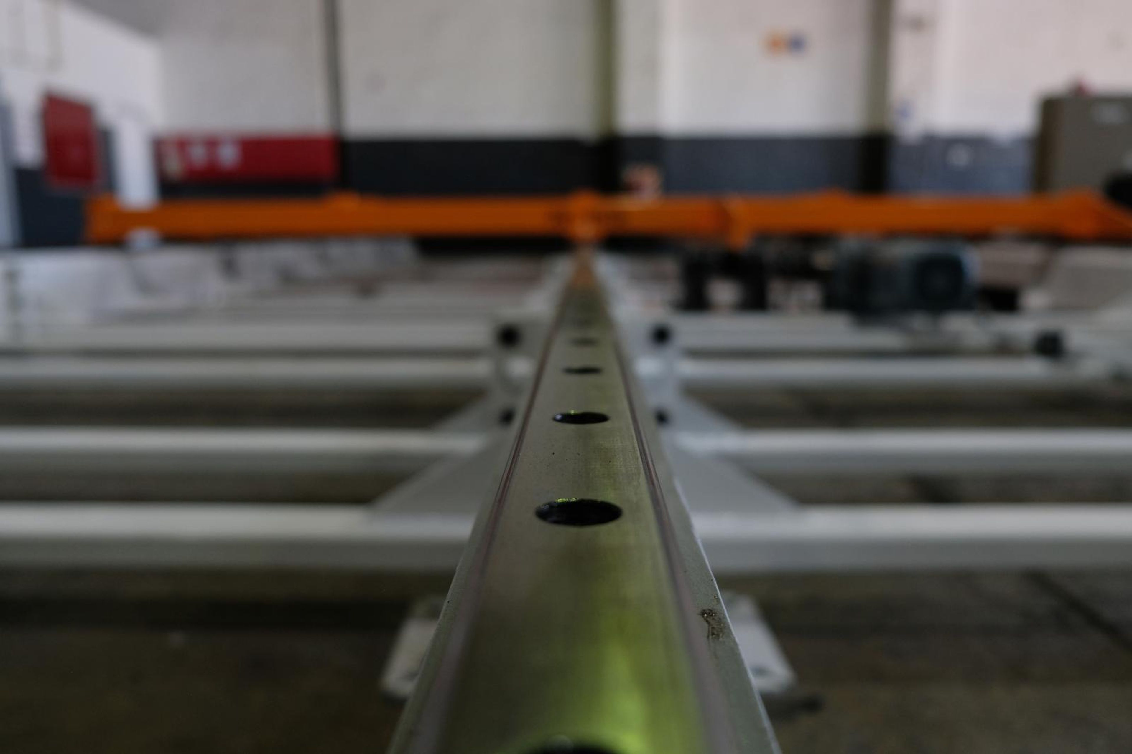 Low view down the central rail toward an orange cross beam