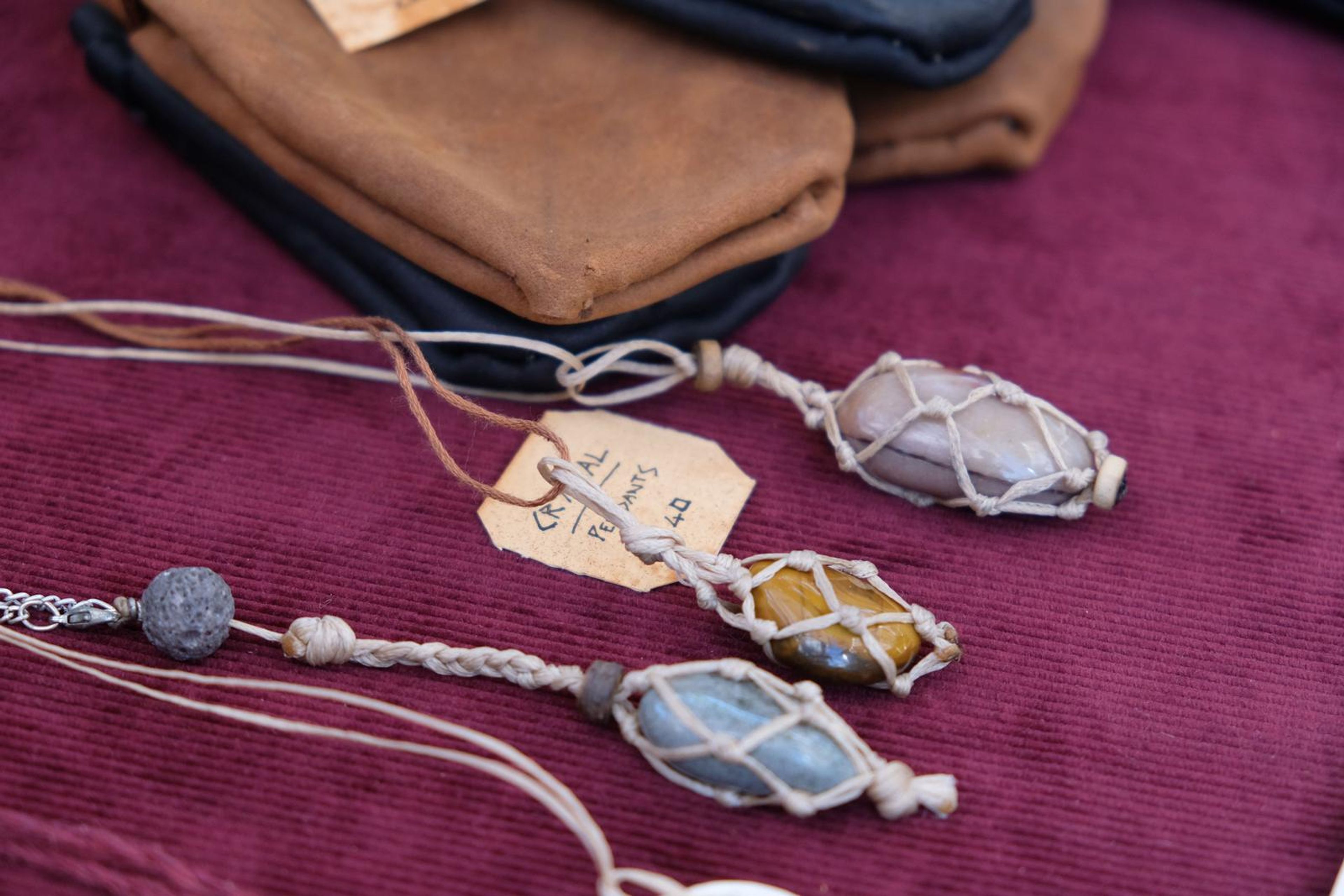 Leather wallets and wire-wrapped crystal pendants on maroon cloth