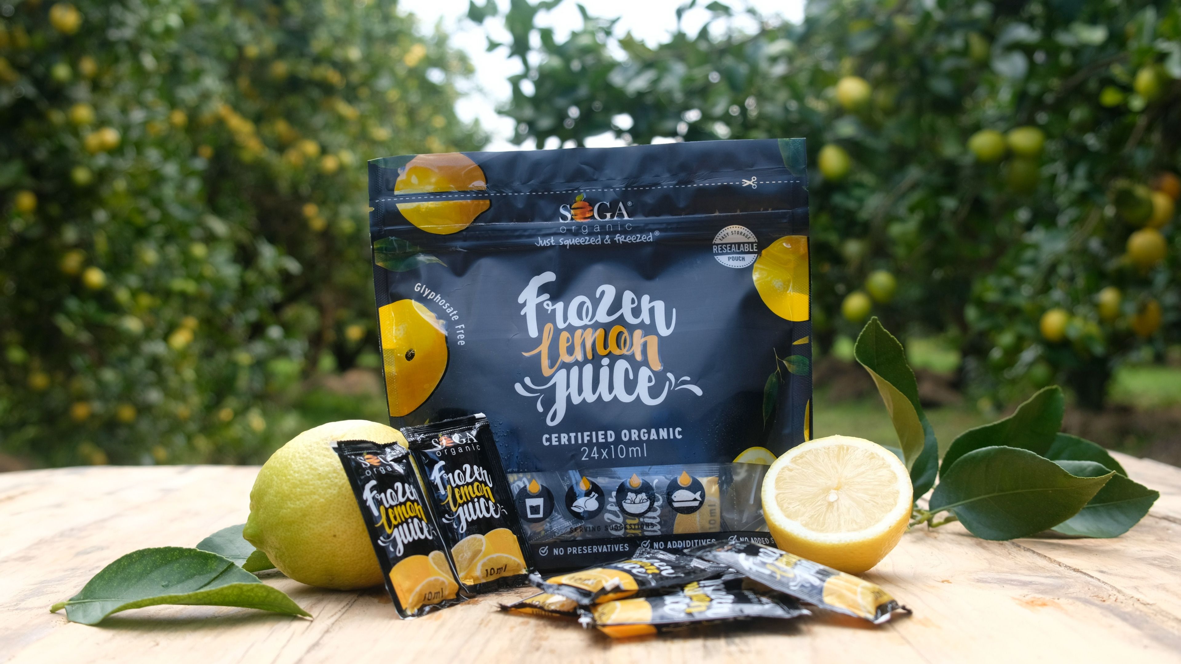 SOGA frozen lemon juice pouch and sachets on a wooden table in a lemon orchard