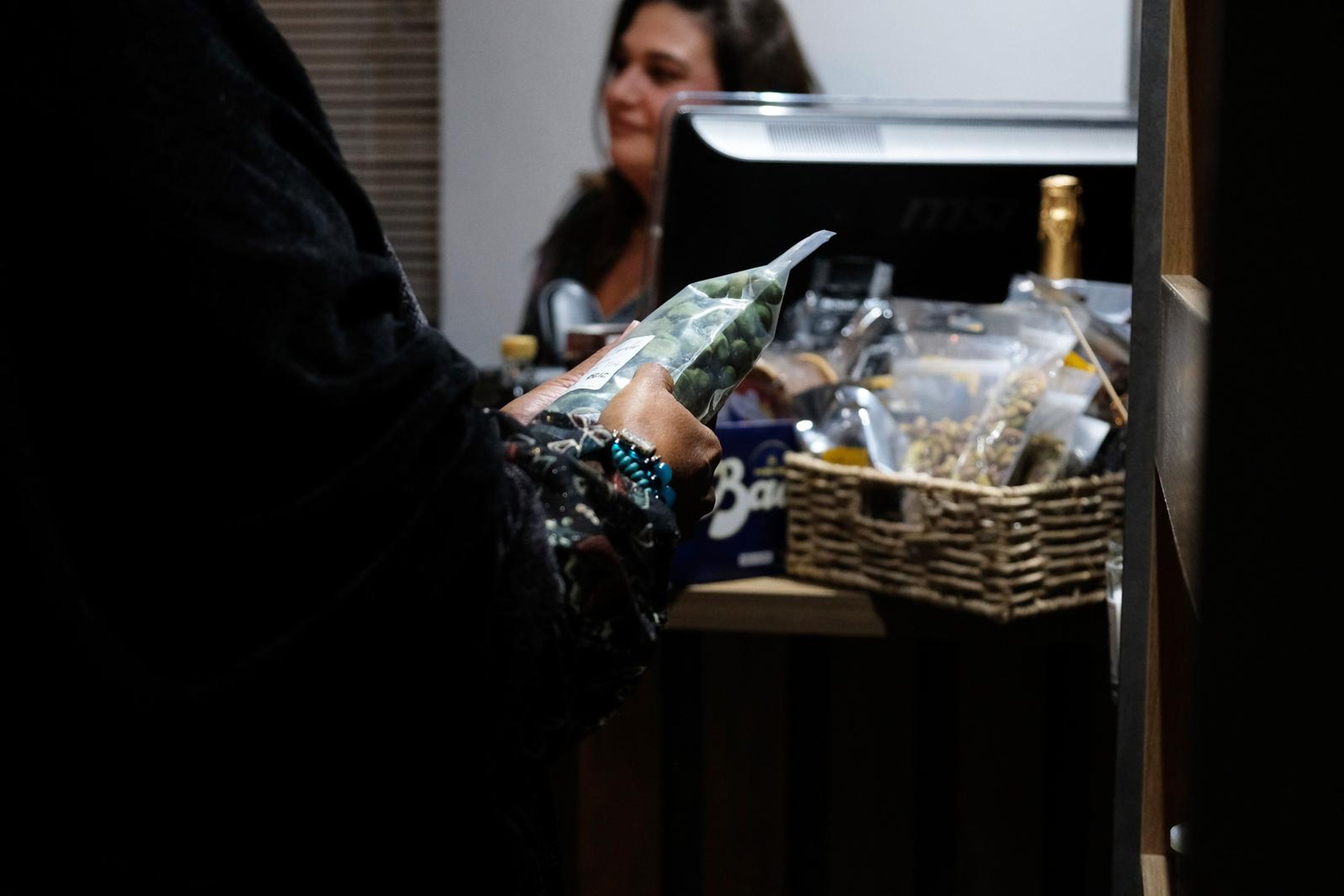 Cashier at the till with a basket of packaged goods