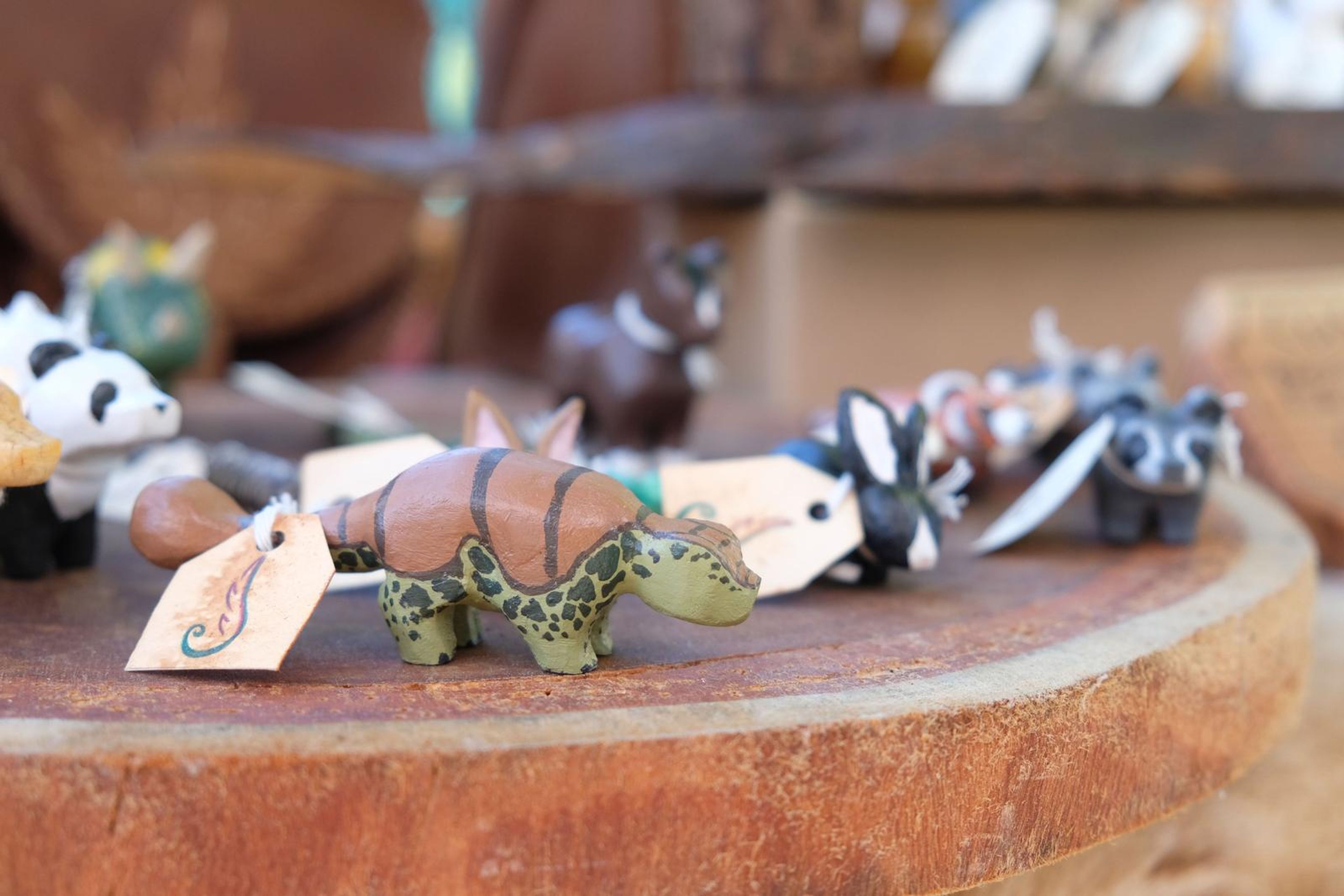Hand-carved wooden animal figures with handwritten tags on a bark slice