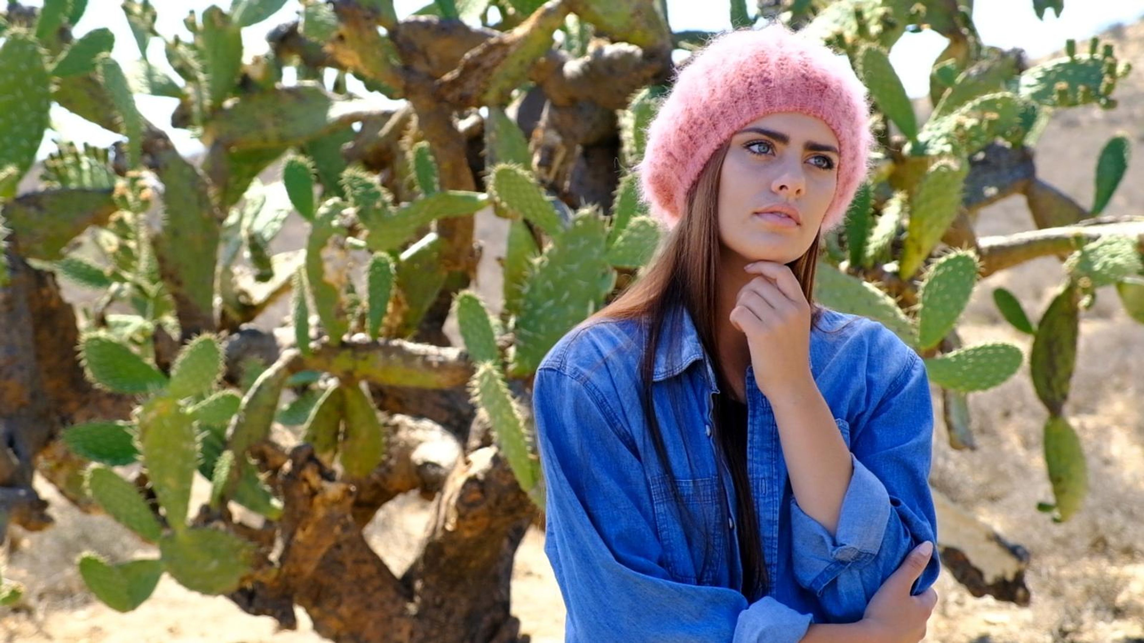 Model in a pink mohair beret and denim jacket among prickly pear