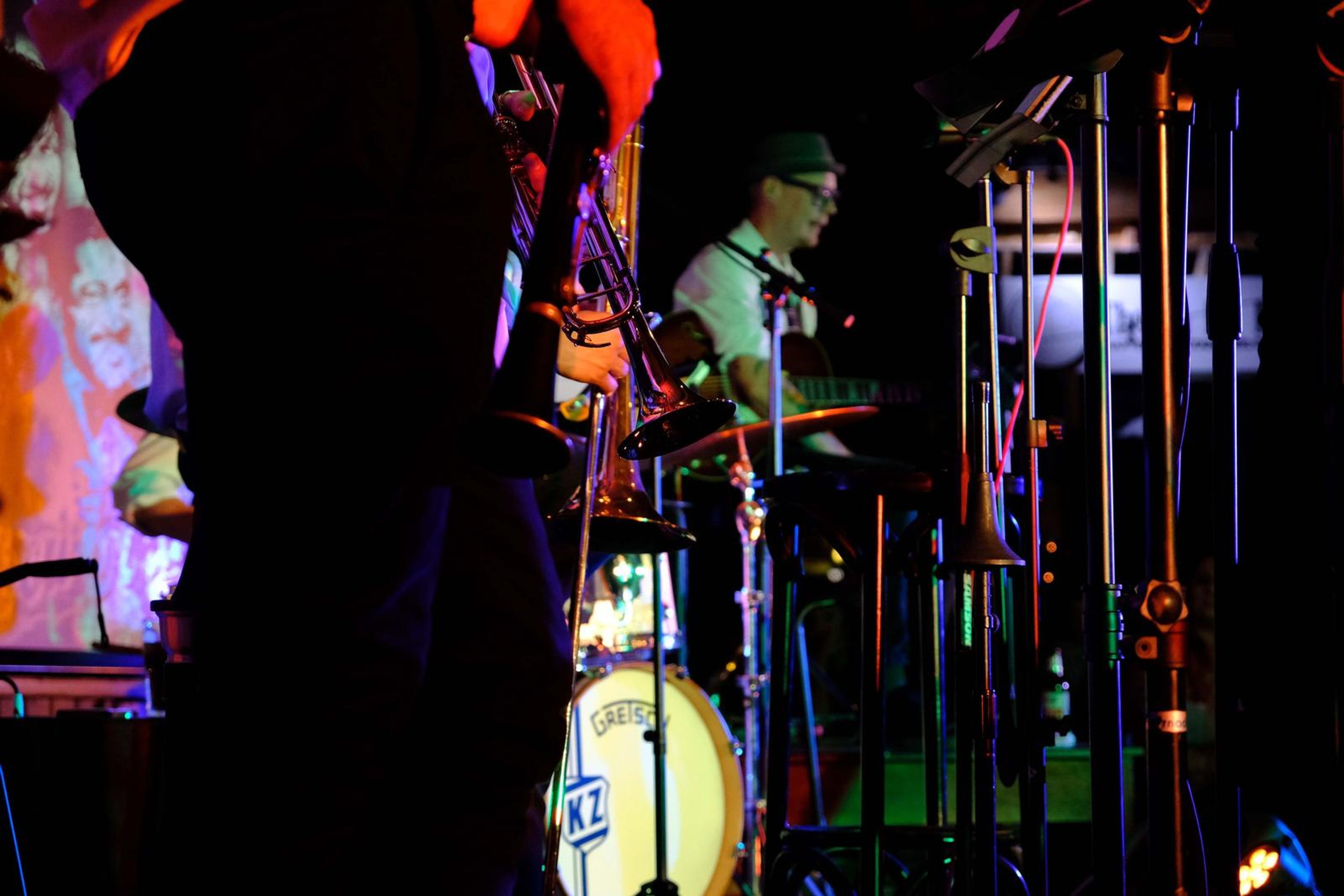 Drummer glimpsed through the microphone stands and horn players
