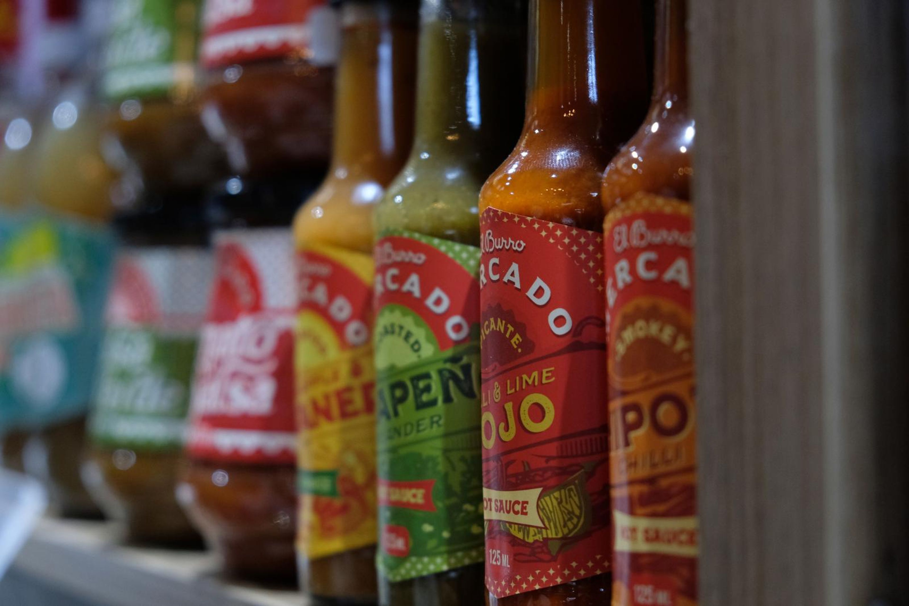Row of El Mercado hot sauce bottles on a shelf
