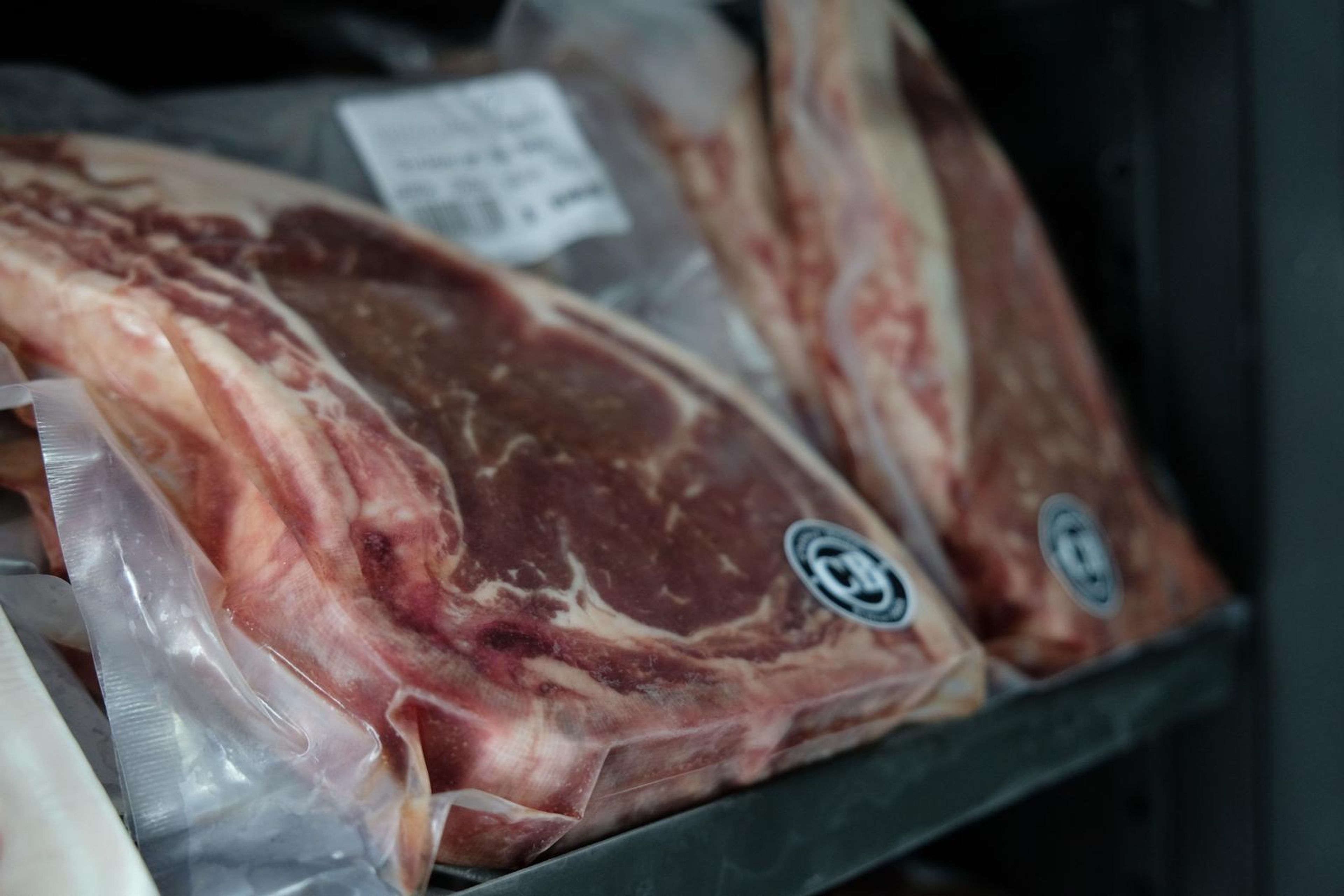 Vacuum-packed beef steaks on a black fridge shelf