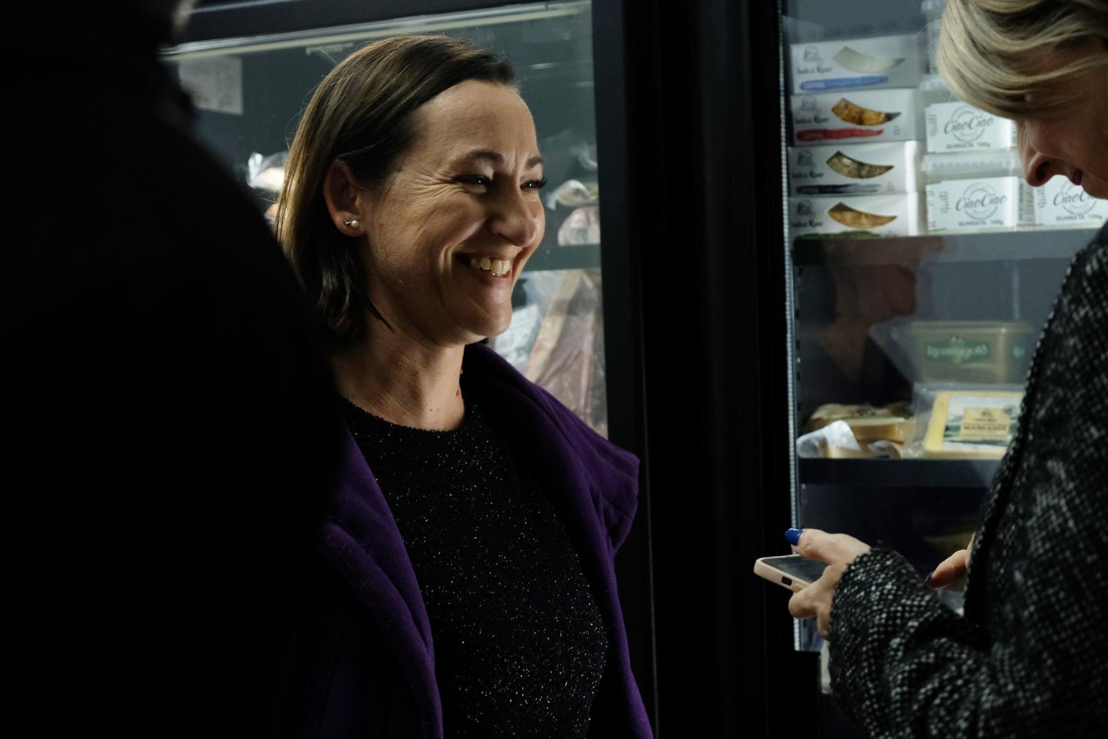 Smiling guest in a purple coat beside the fridge cabinets