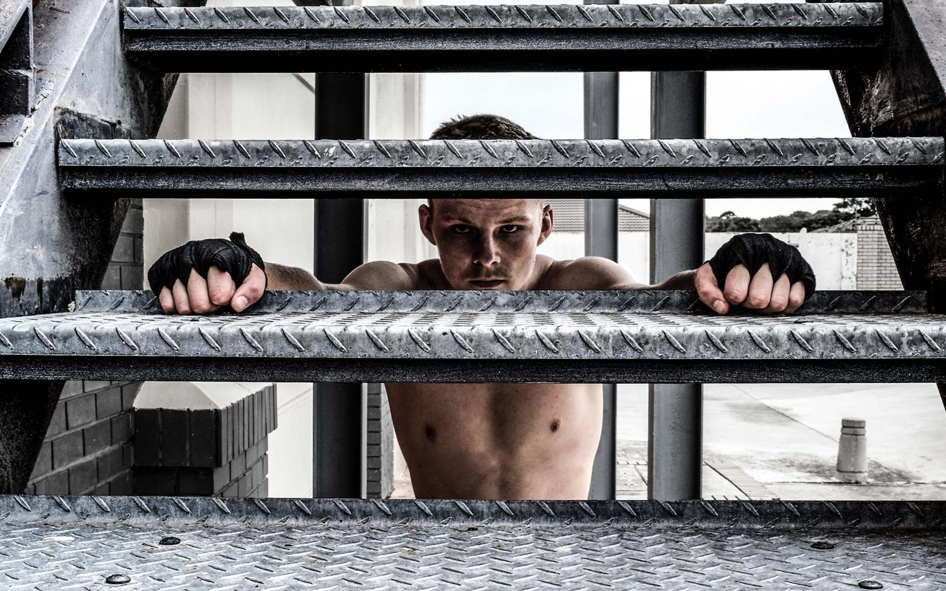 Fighter's face and wrapped fists seen between the steps of a metal stair