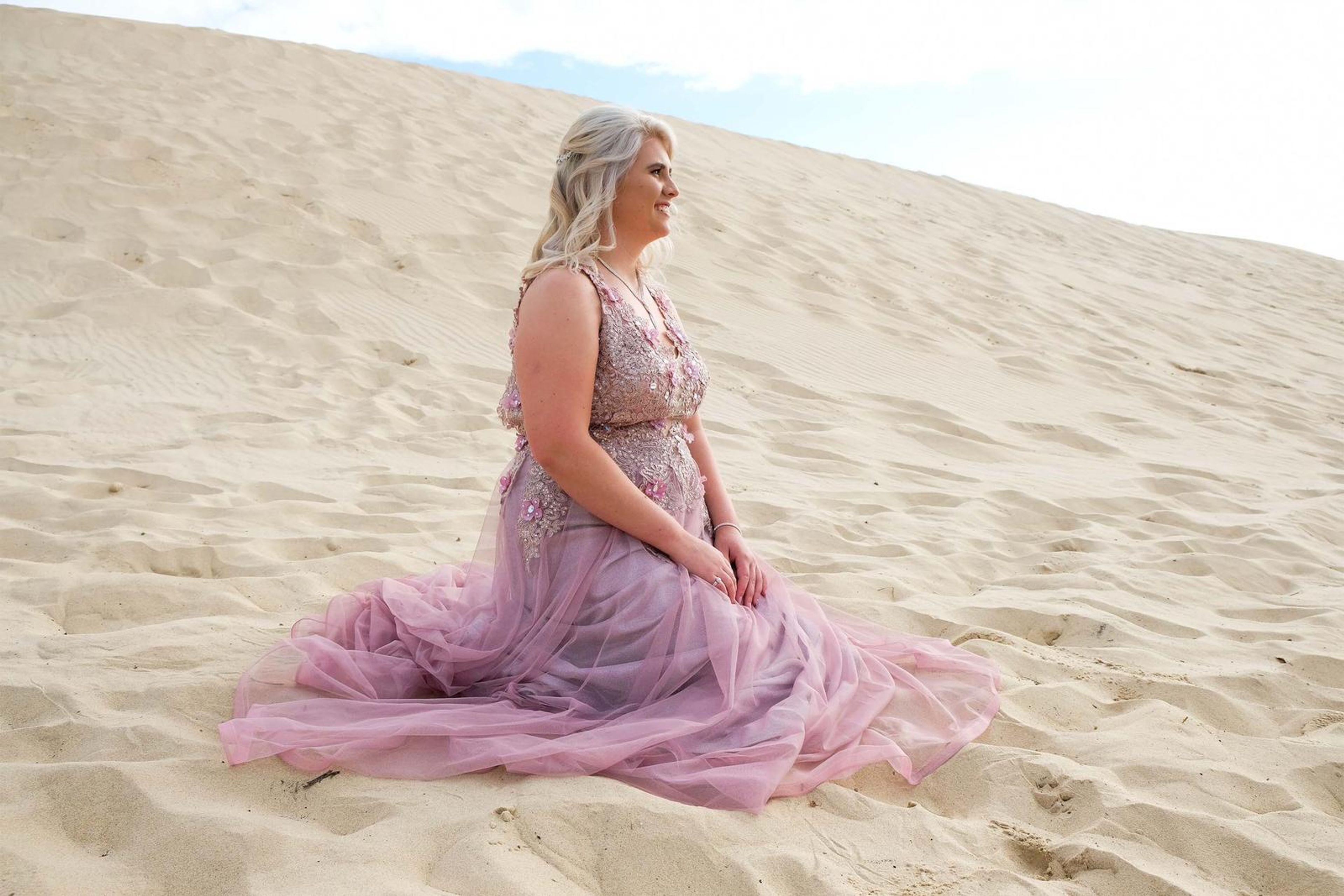 Sitting on a dune with the gown spread across the sand