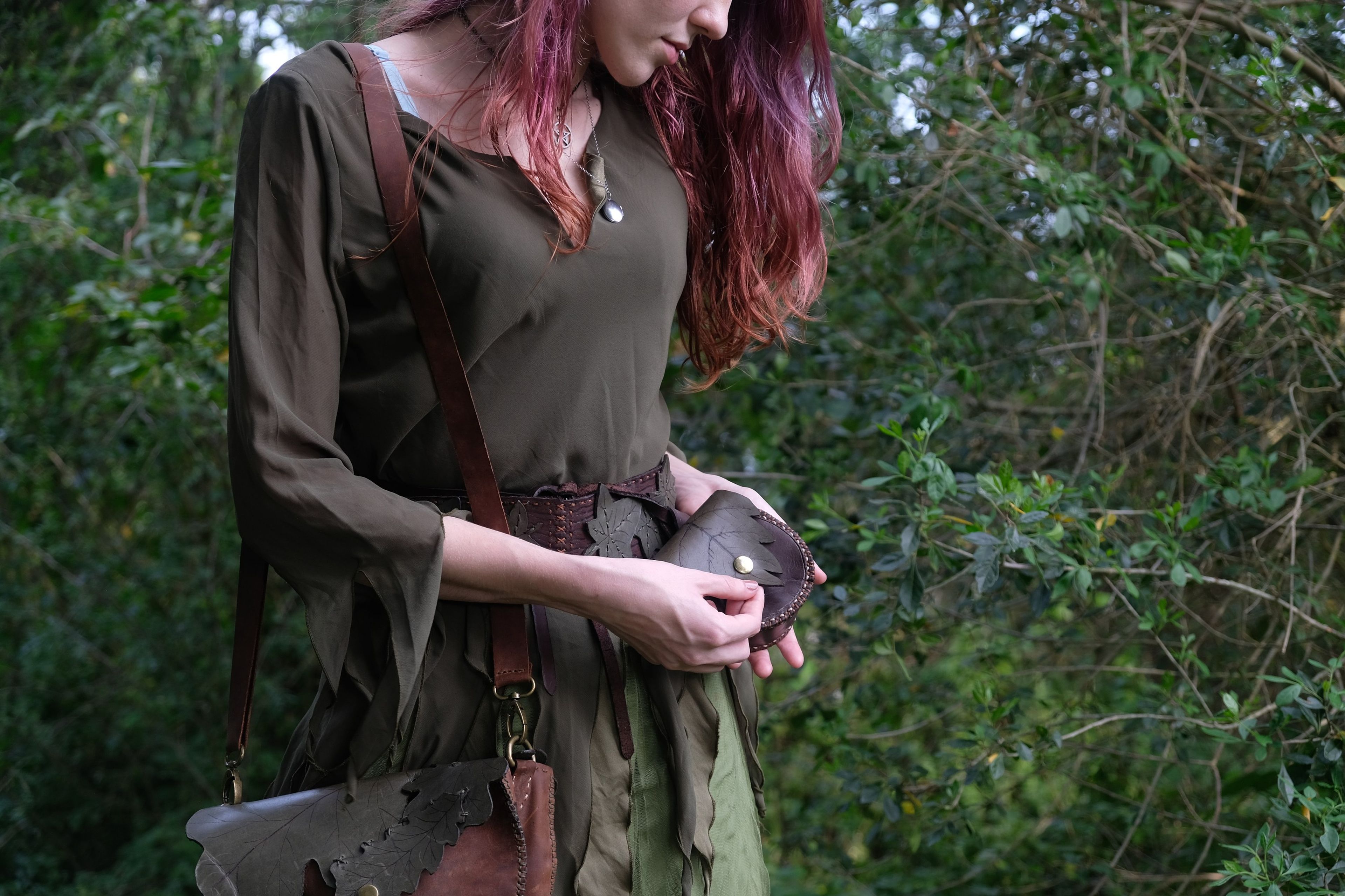 Woman in green looking down at the leather bag in her hands