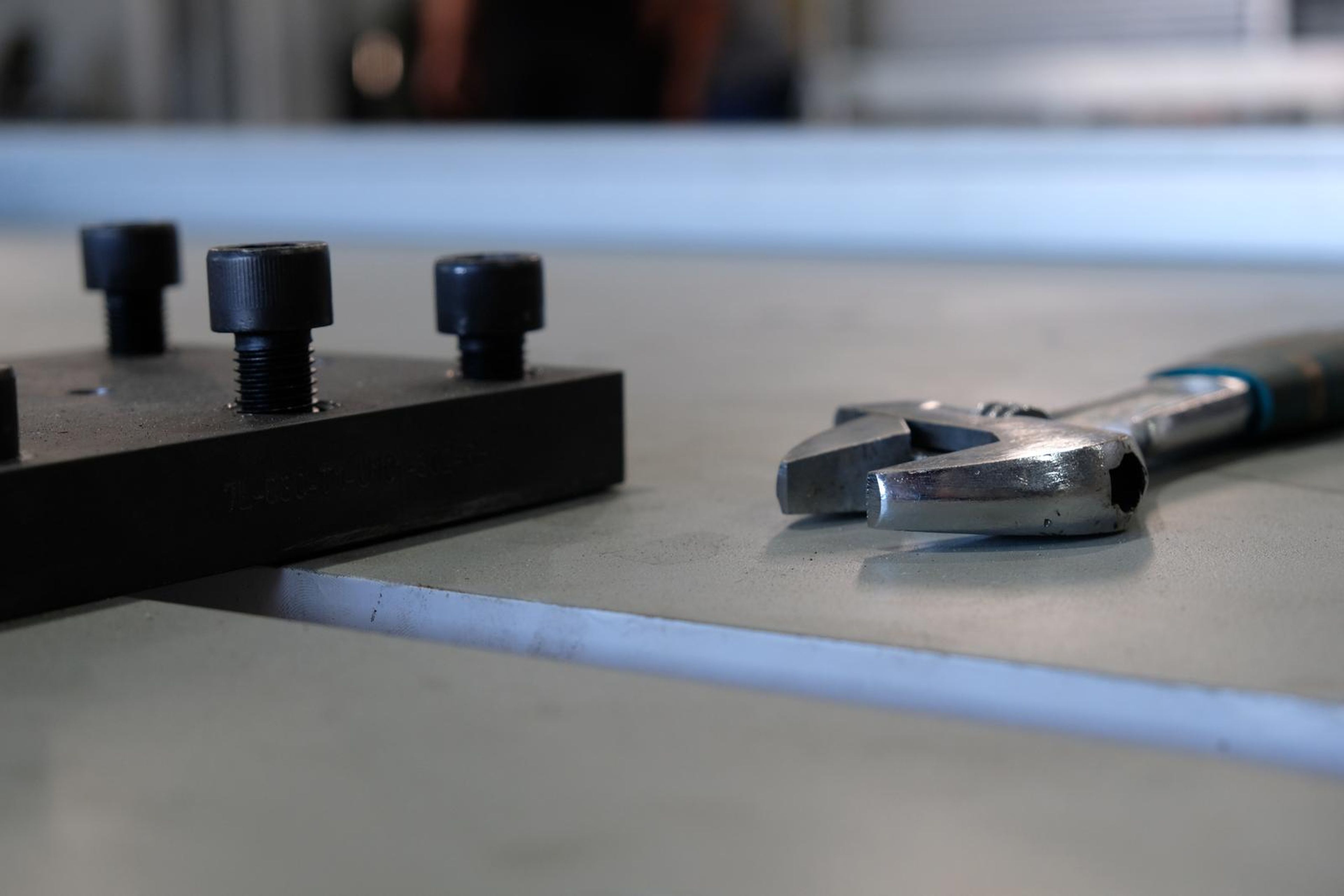 Black bolt plate and a spanner on a grey steel table