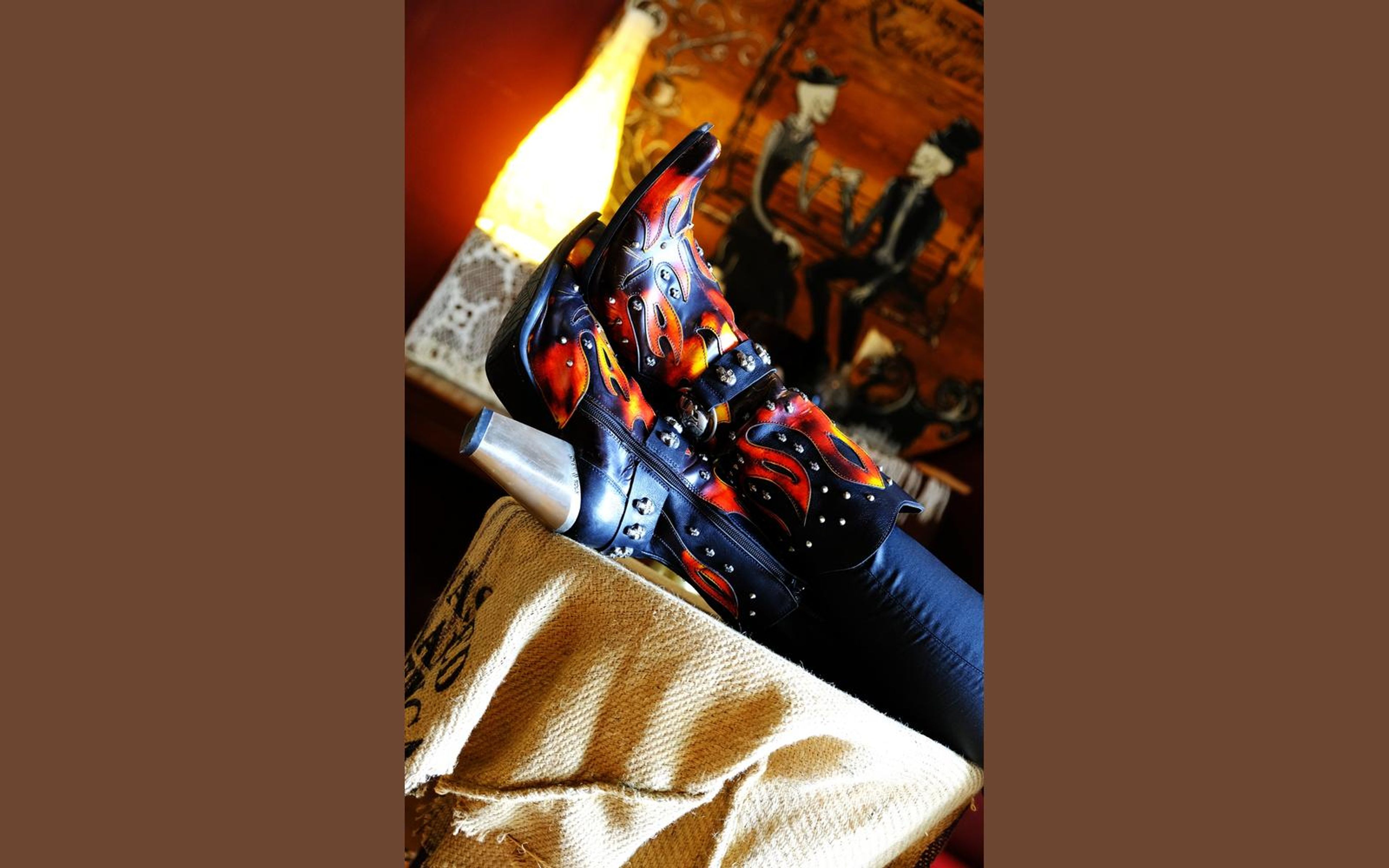 Flame-painted black boot propped on a hessian coffee sack, a skull glass beside it