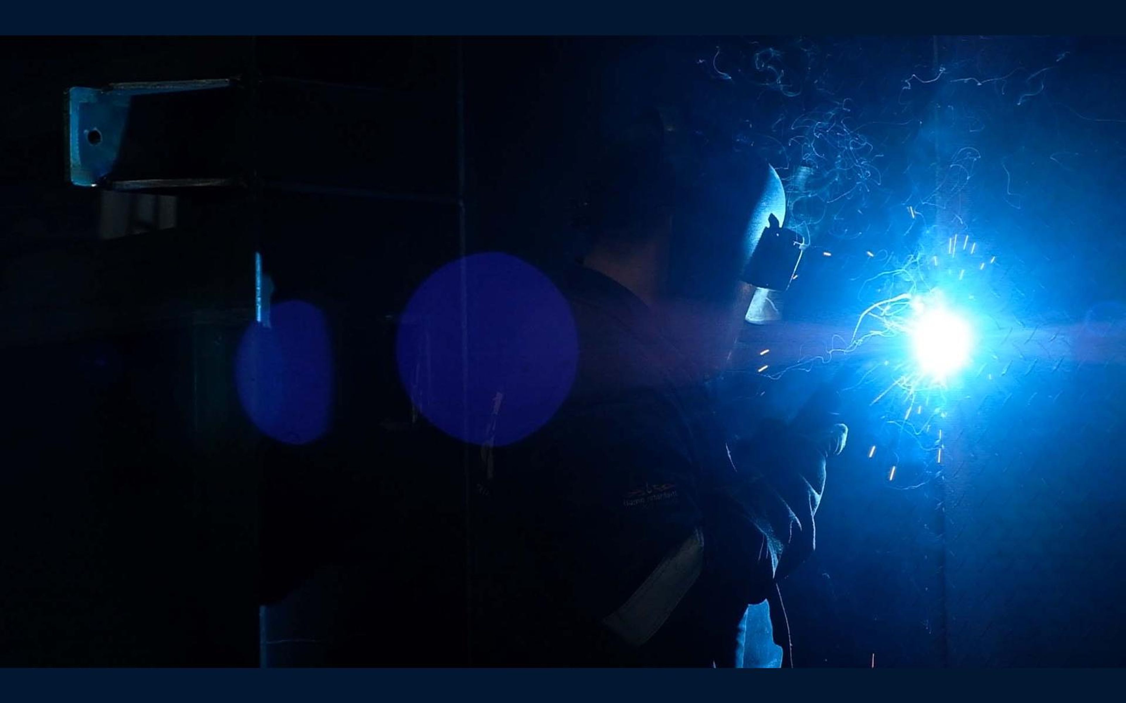 Welder in the dark with a bright arc and sparks
