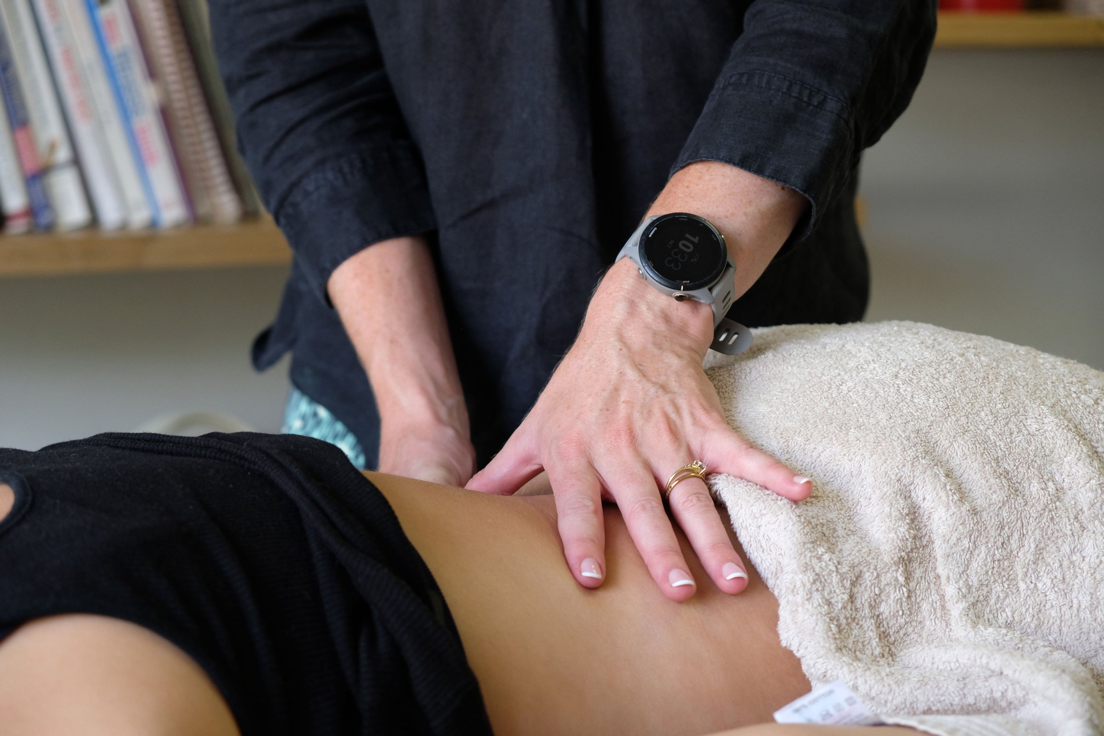 A therapist's hands working on a client's lower back during a treatment session