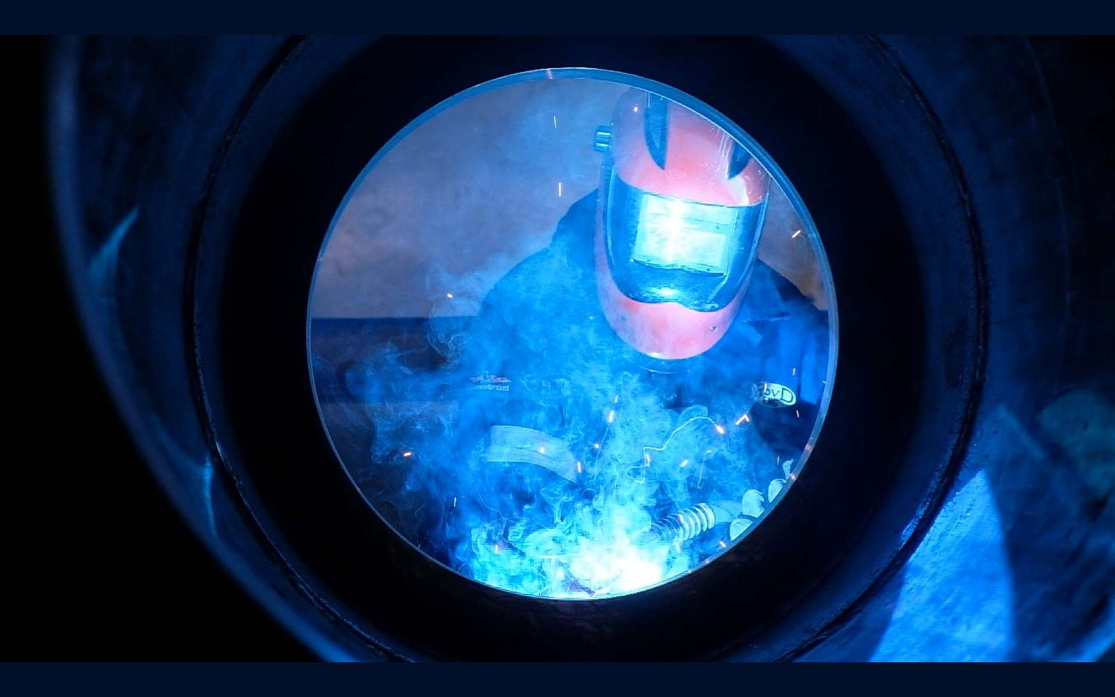 Welder framed by a circular steel tube while welding
