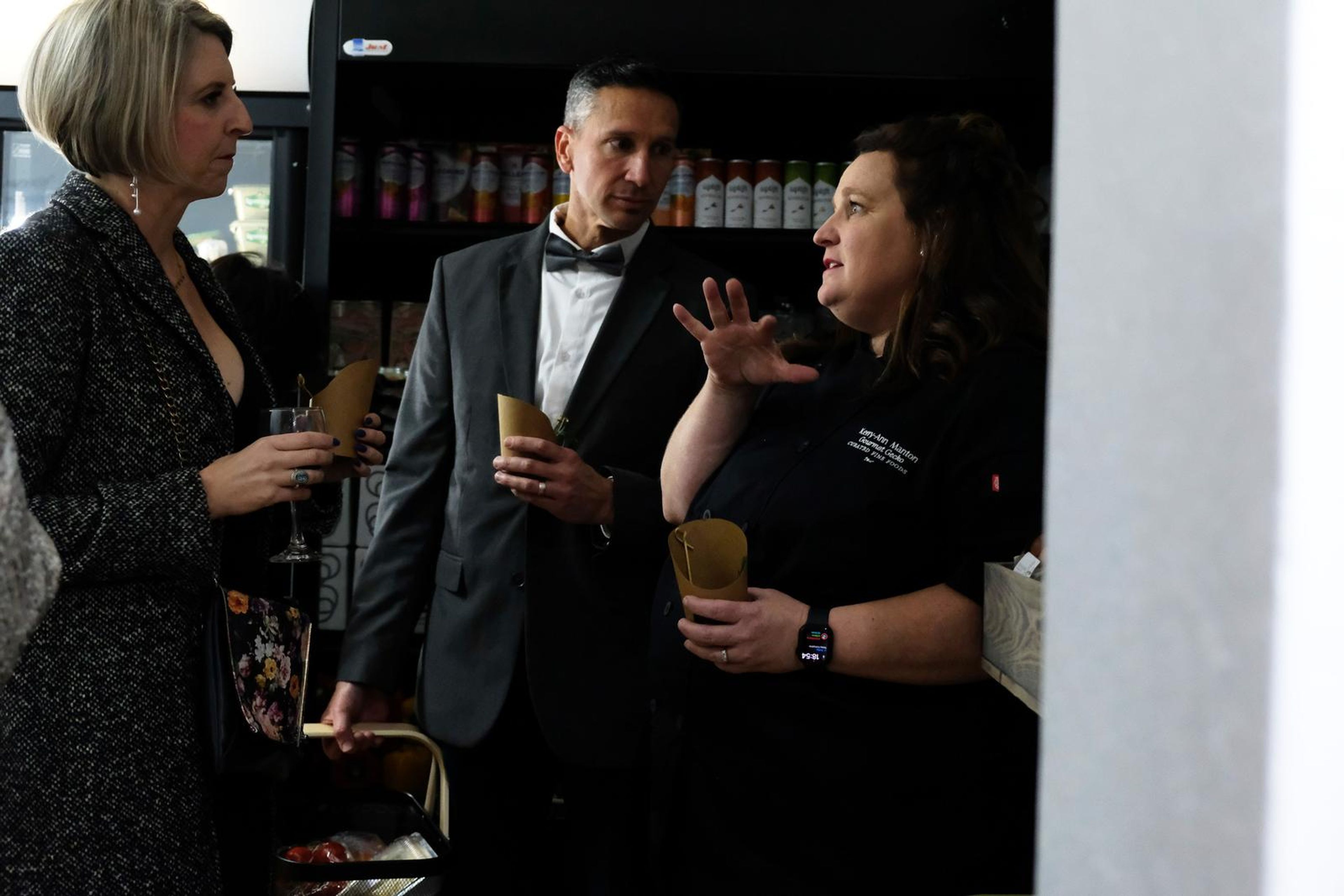 Three guests chatting, one gesturing, at the opening
