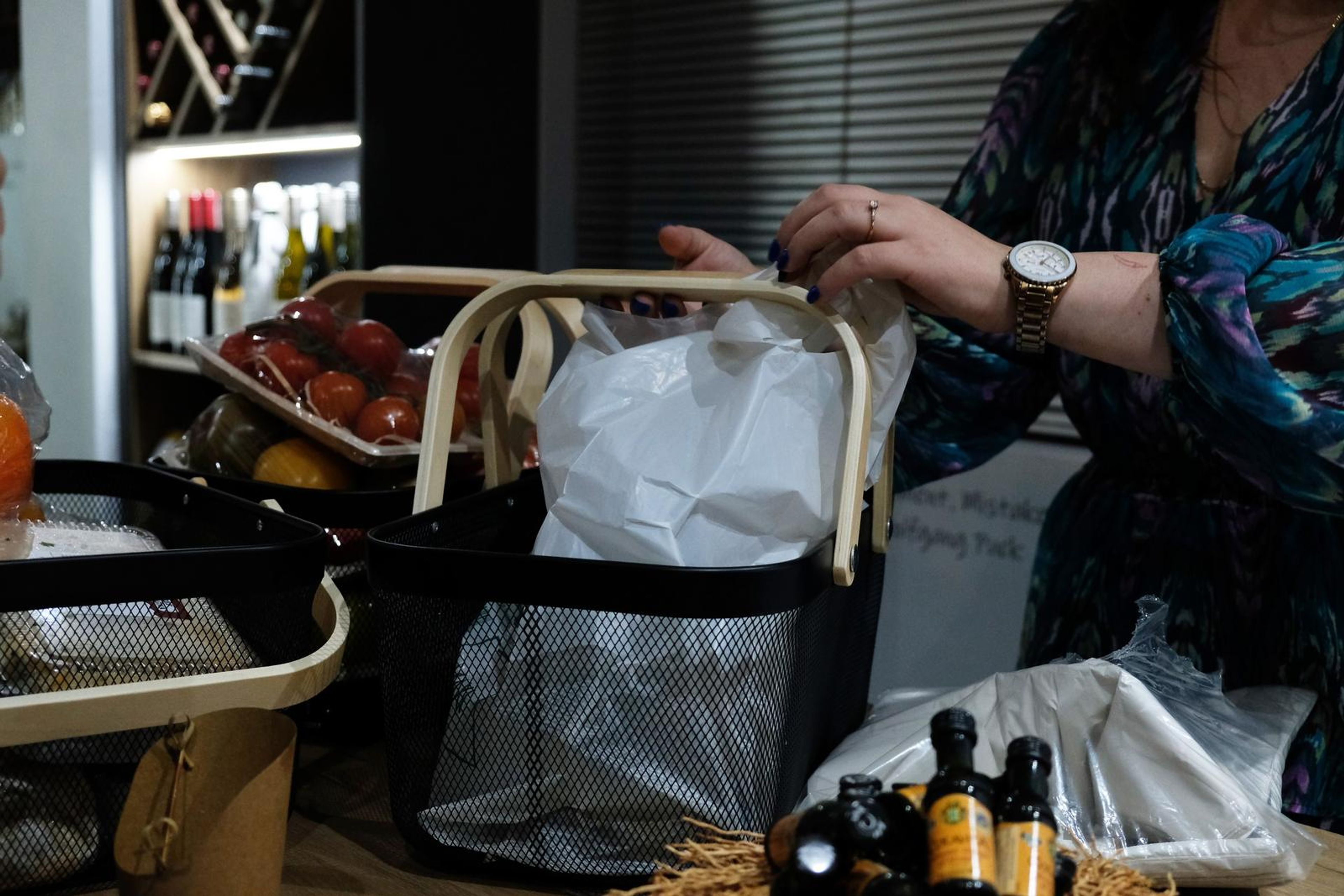 Cashier bagging groceries beside a full basket