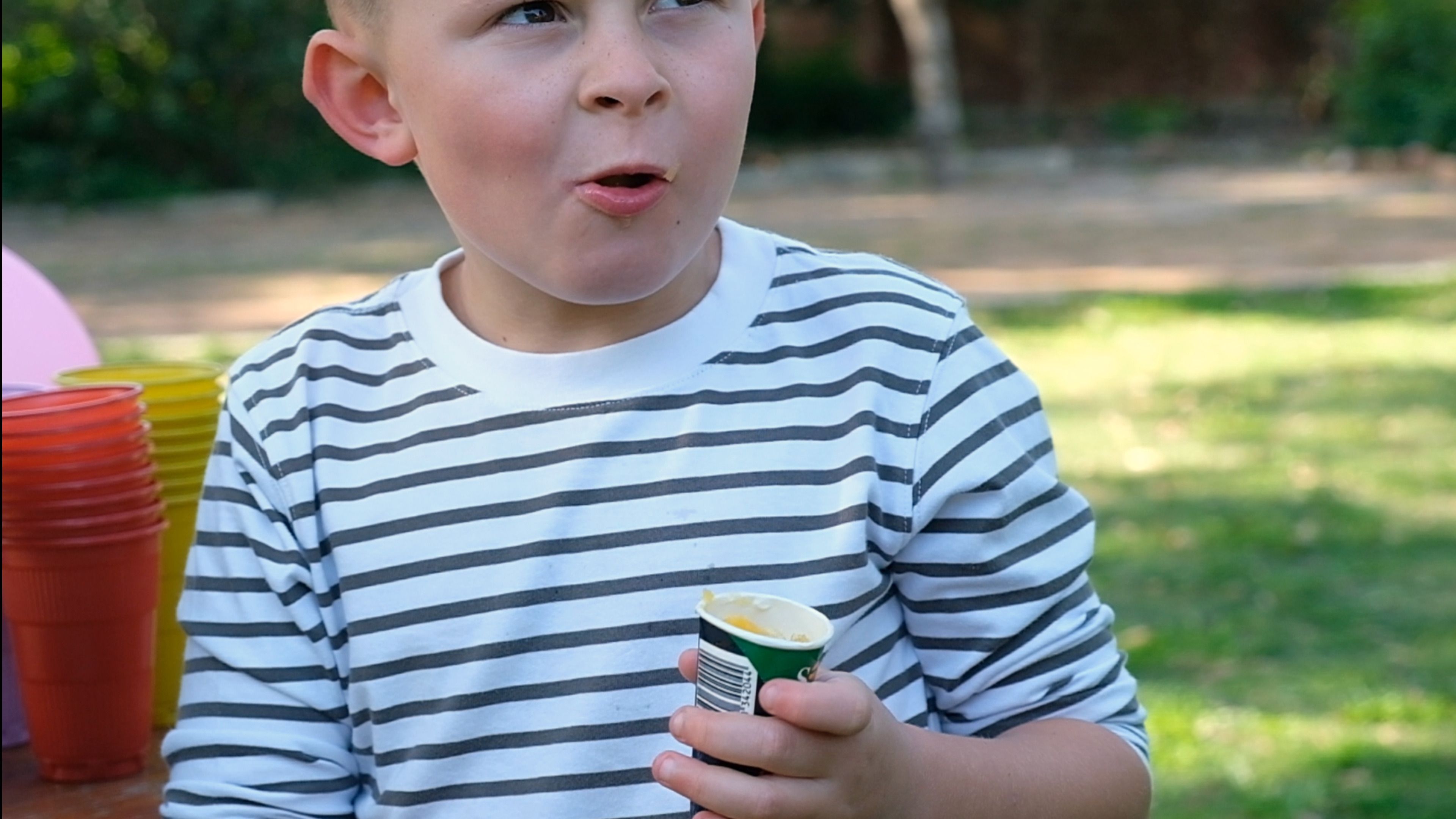 Excited boy holding a frozen orange treat outdoors