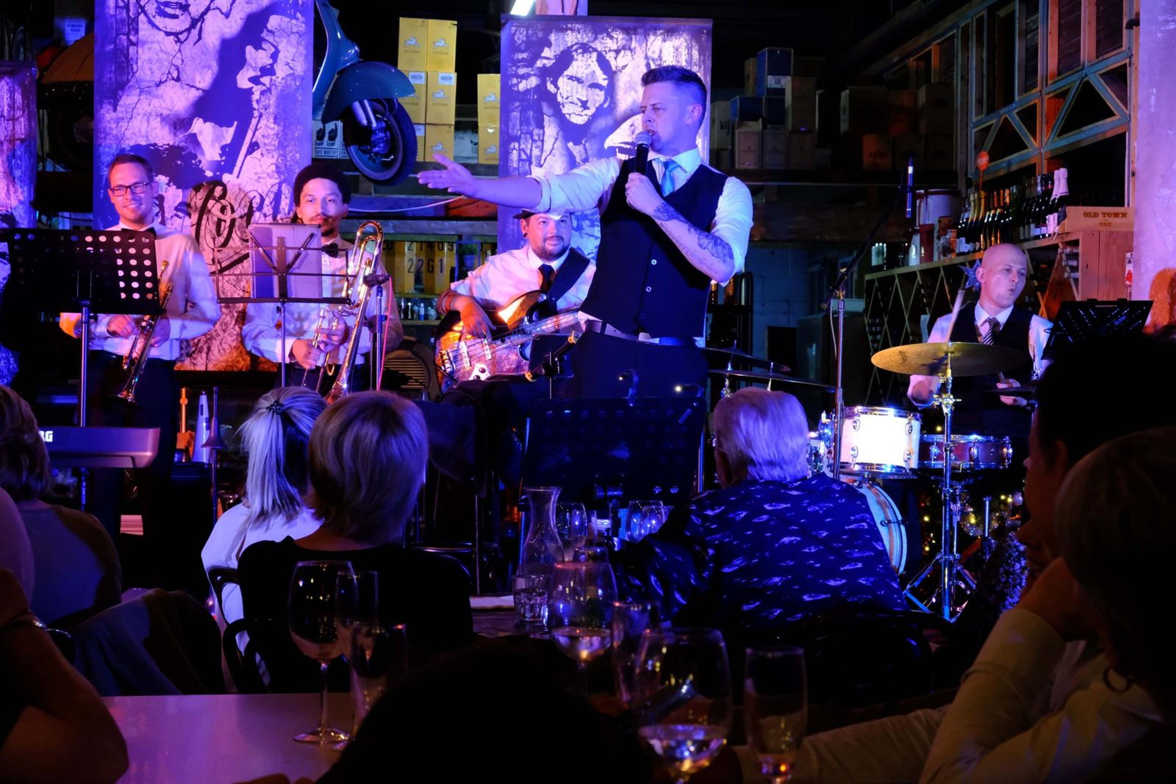 Singer on stage in front of a jazz mural with the band around him